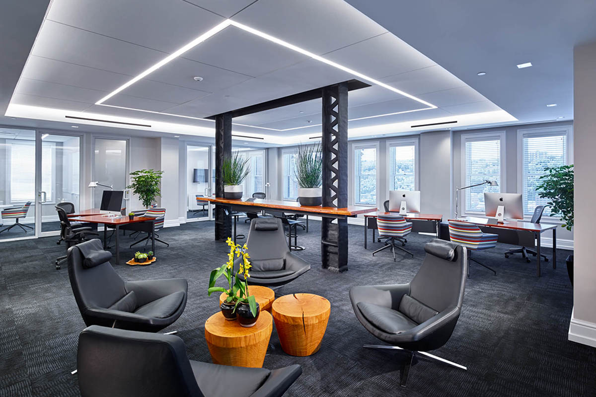 Modern office space with desks, chairs, and indoor plants.