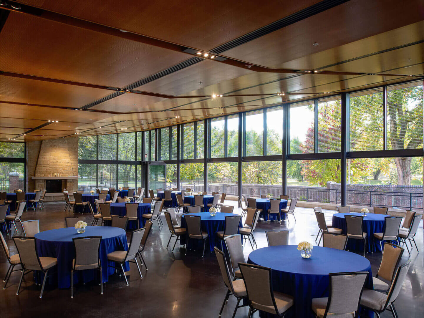 A spacious dining room with round tables and large windows.