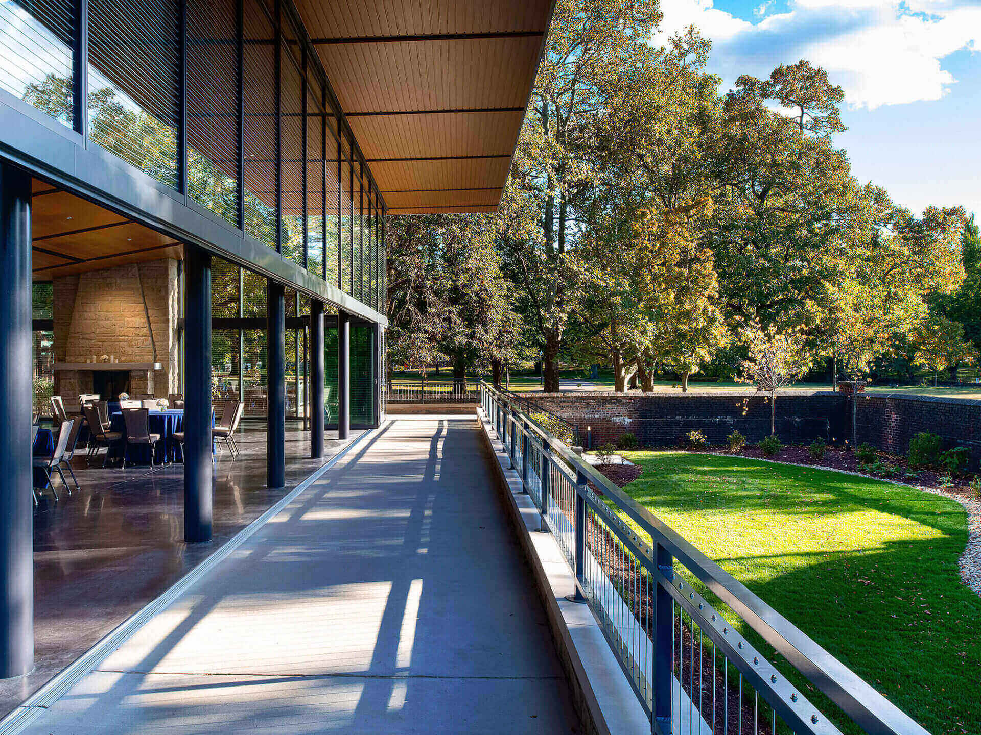Modern balcony overlooking a green lawn and trees on a sunny day.