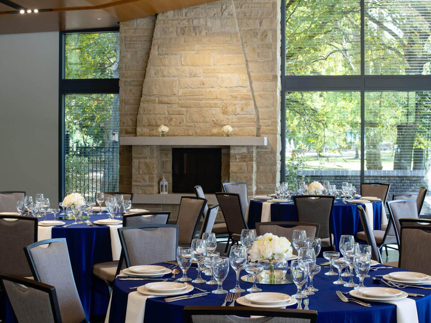 Elegant dining setup in a room with large windows and a stone fireplace.