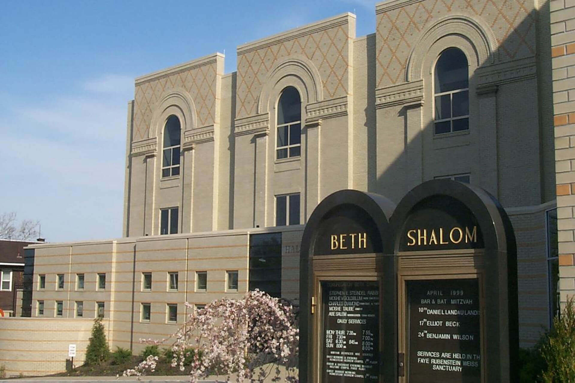 Exterior of a beige stone building with arched windows and a sign reading 'Beth Shalom'.