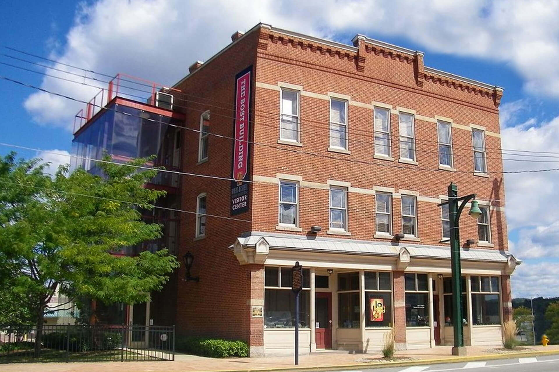 Historic three-story brick building on a street corner under a blue sky.