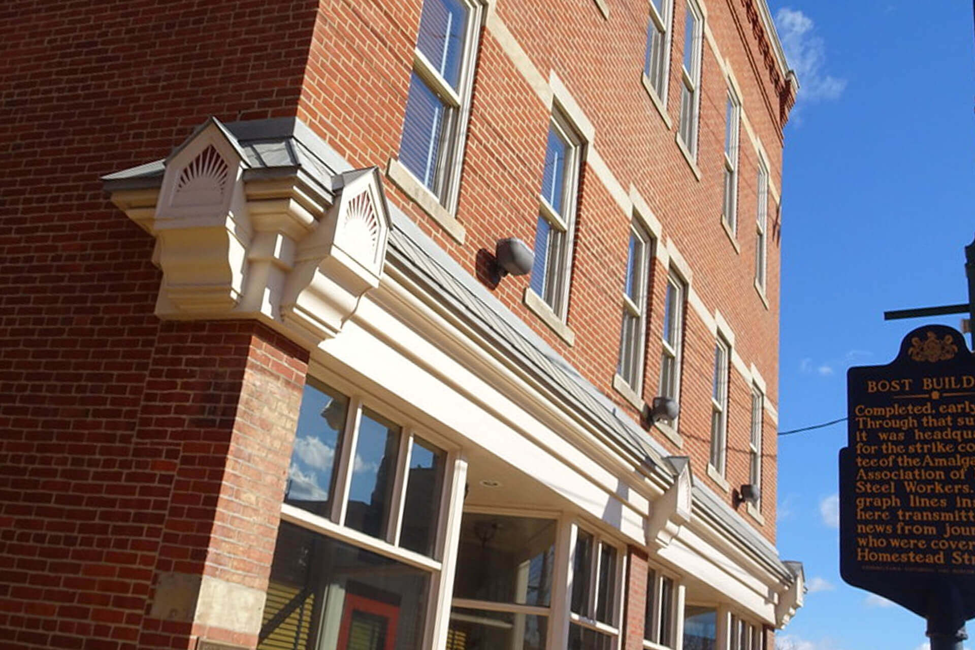 Close-up of a brick building with windows and decorative cornices.