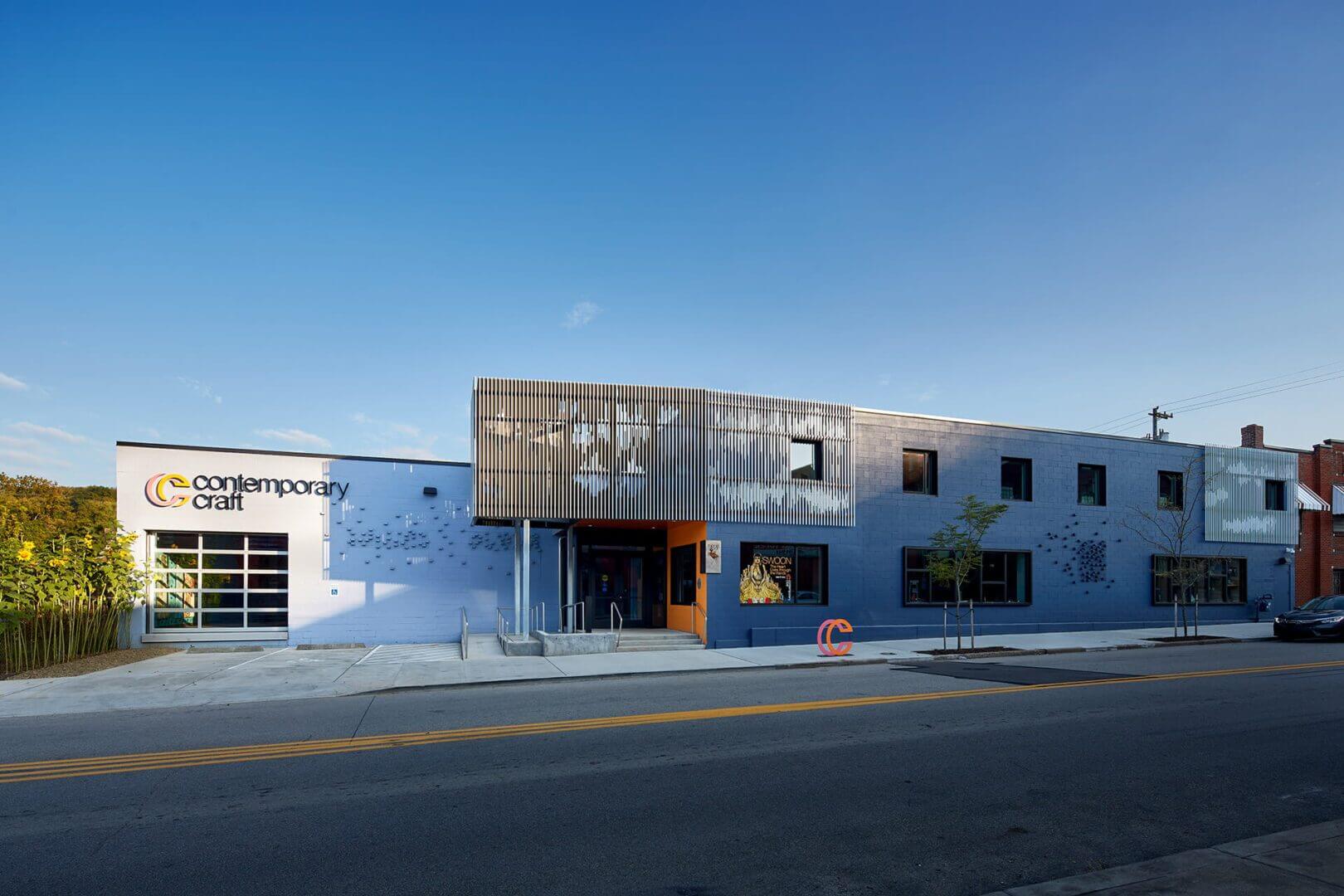 Modern industrial building with wooden panel accents under a clear blue sky.