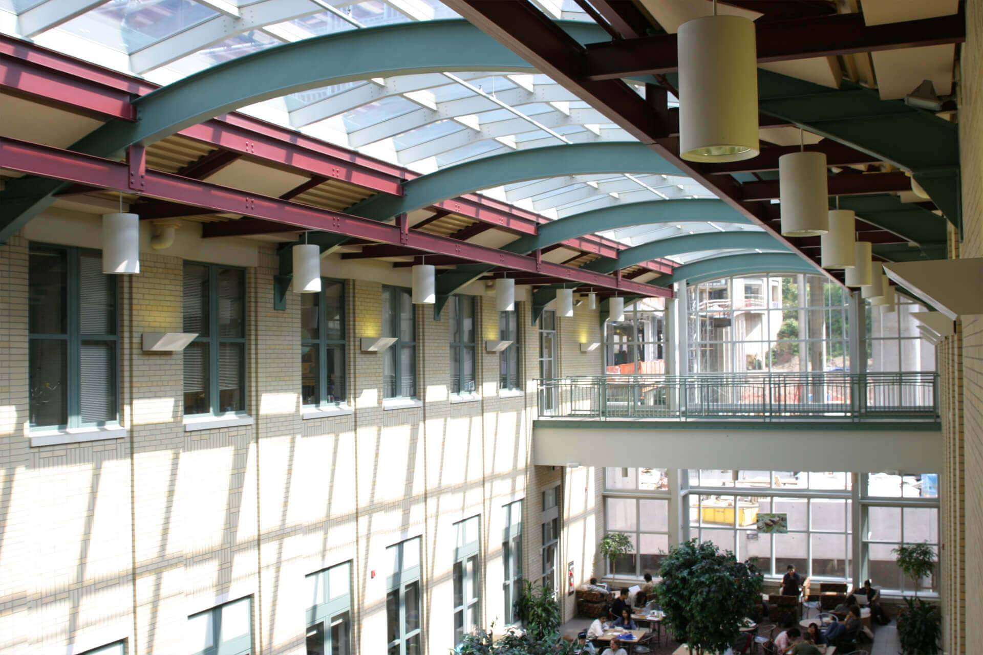 Modern indoor atrium with glass ceiling and plants.