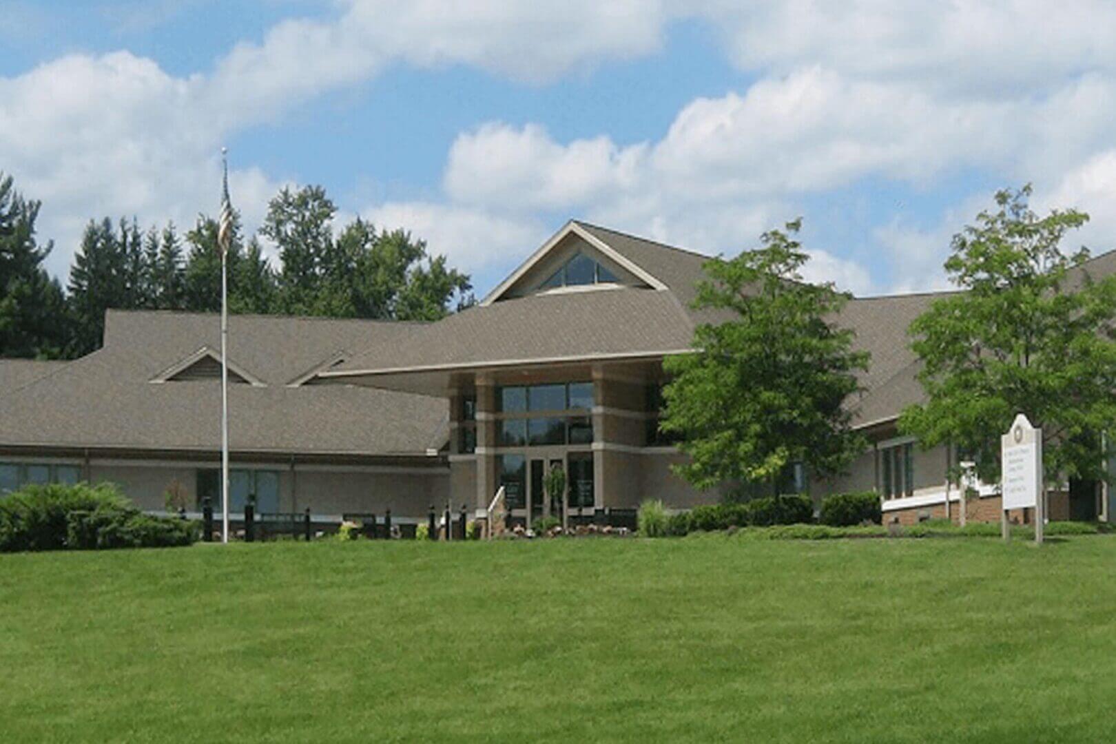A modern building with large windows and a green lawn under a blue sky.