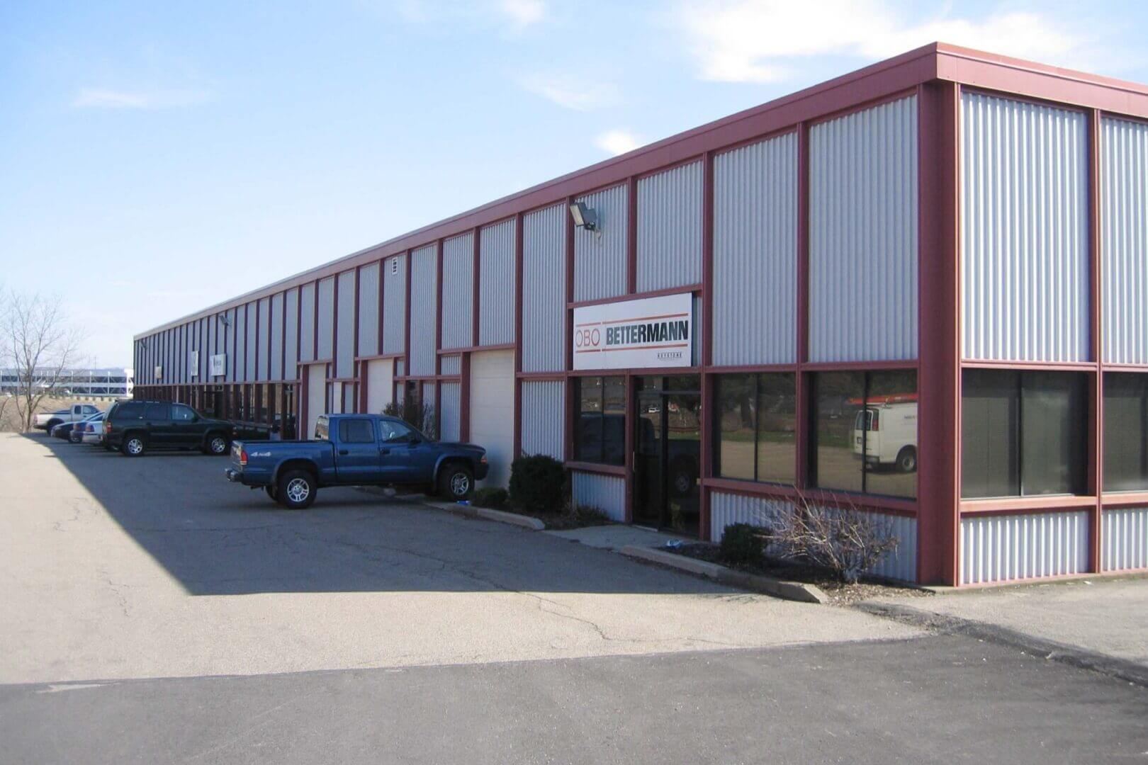 Exterior view of a commercial building with a parking lot and pickup trucks.