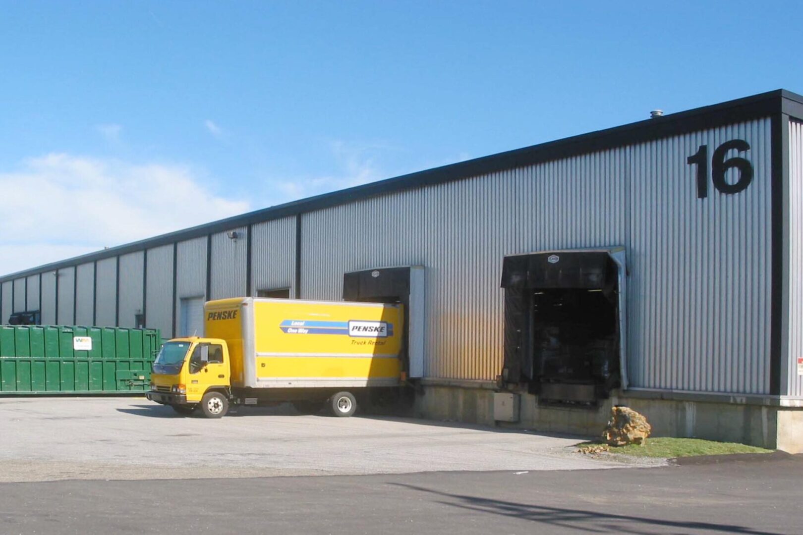 A yellow delivery truck parked at a warehouse loading dock.