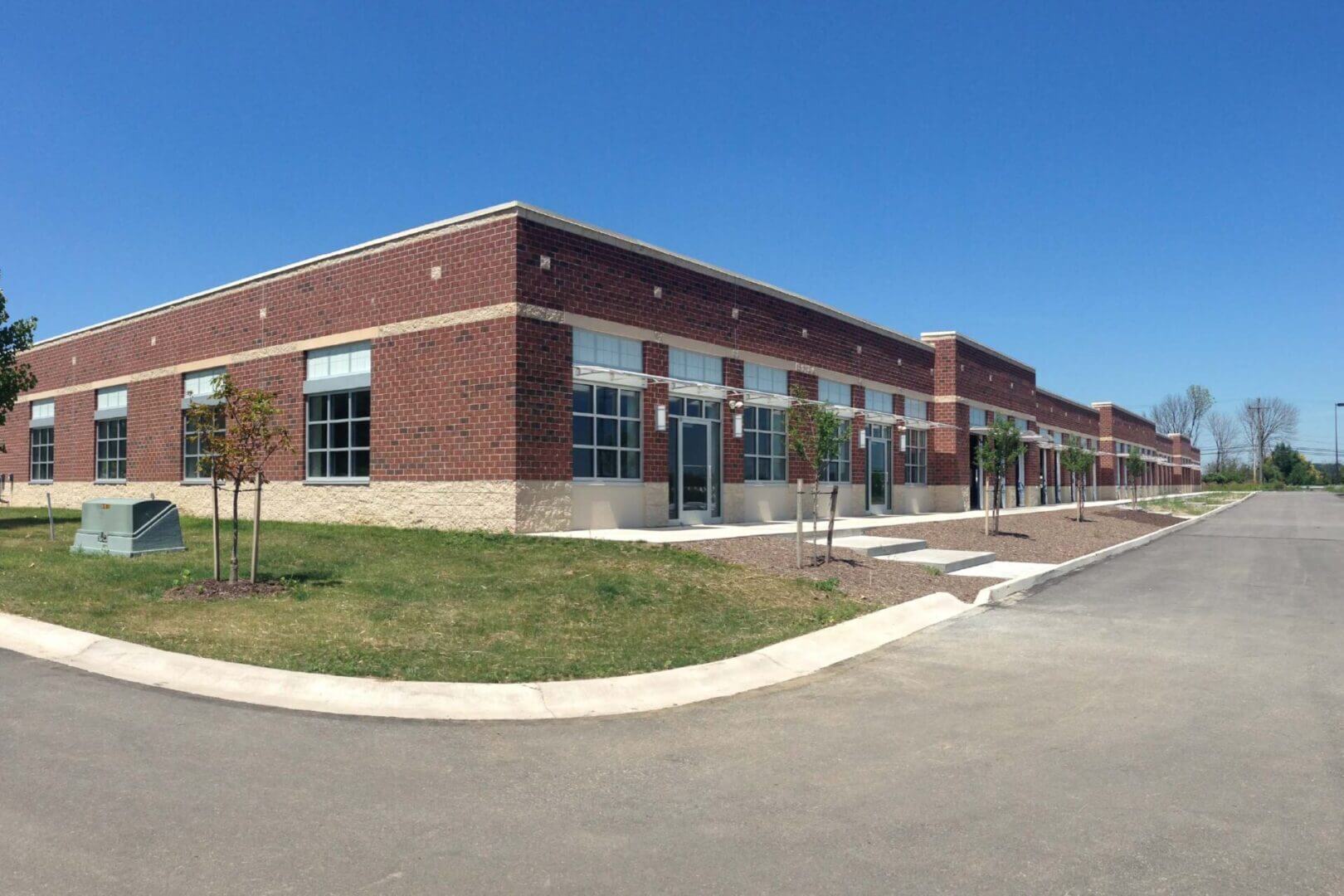 A modern brick commercial building with large glass windows under a clear blue sky.