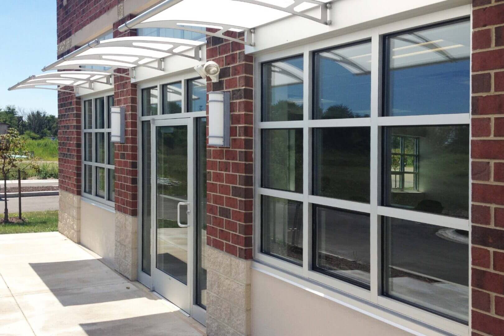 Modern exterior wall with large windows and a door under a metal awning.