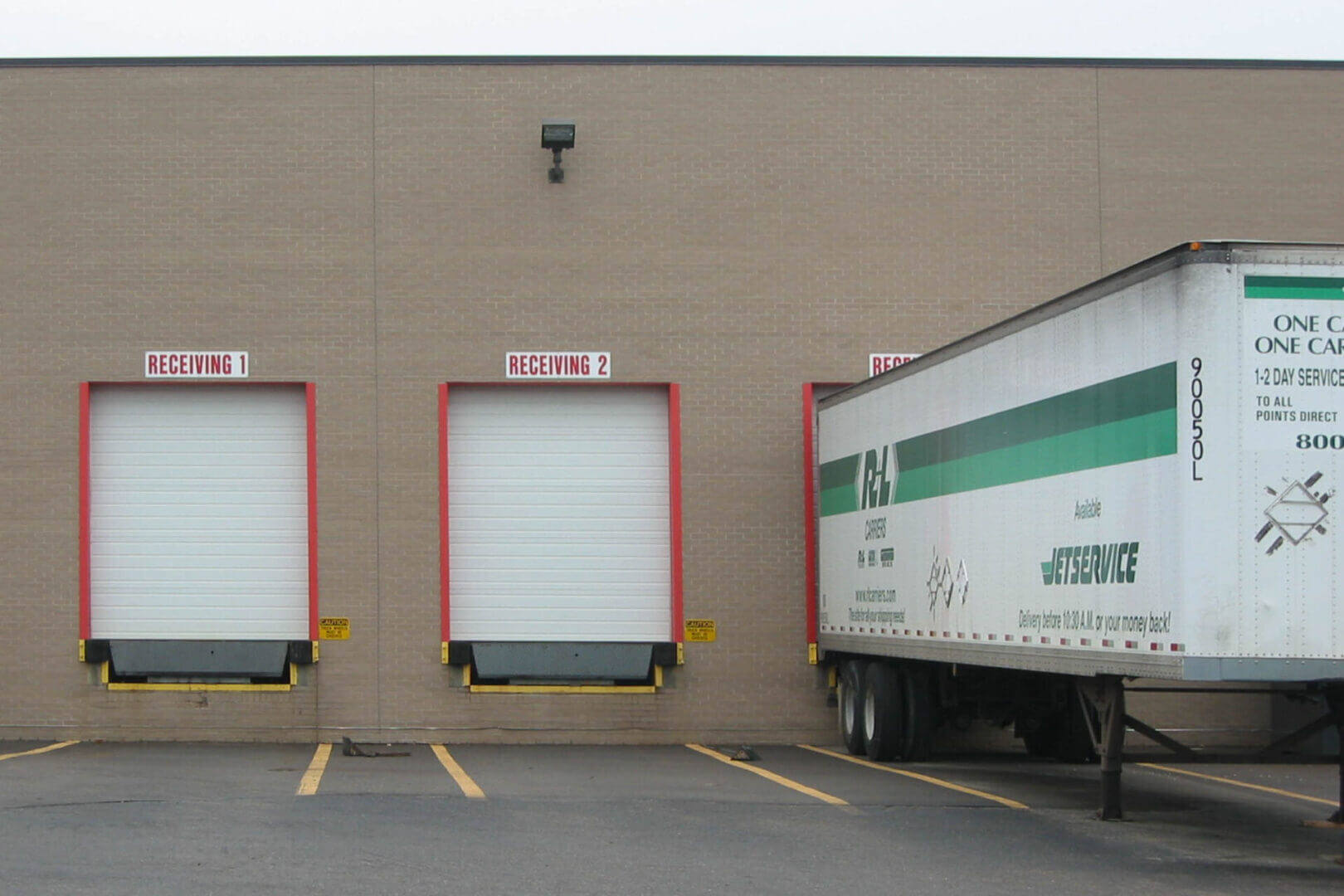 A truck backed up to a loading dock beside two empty docks.