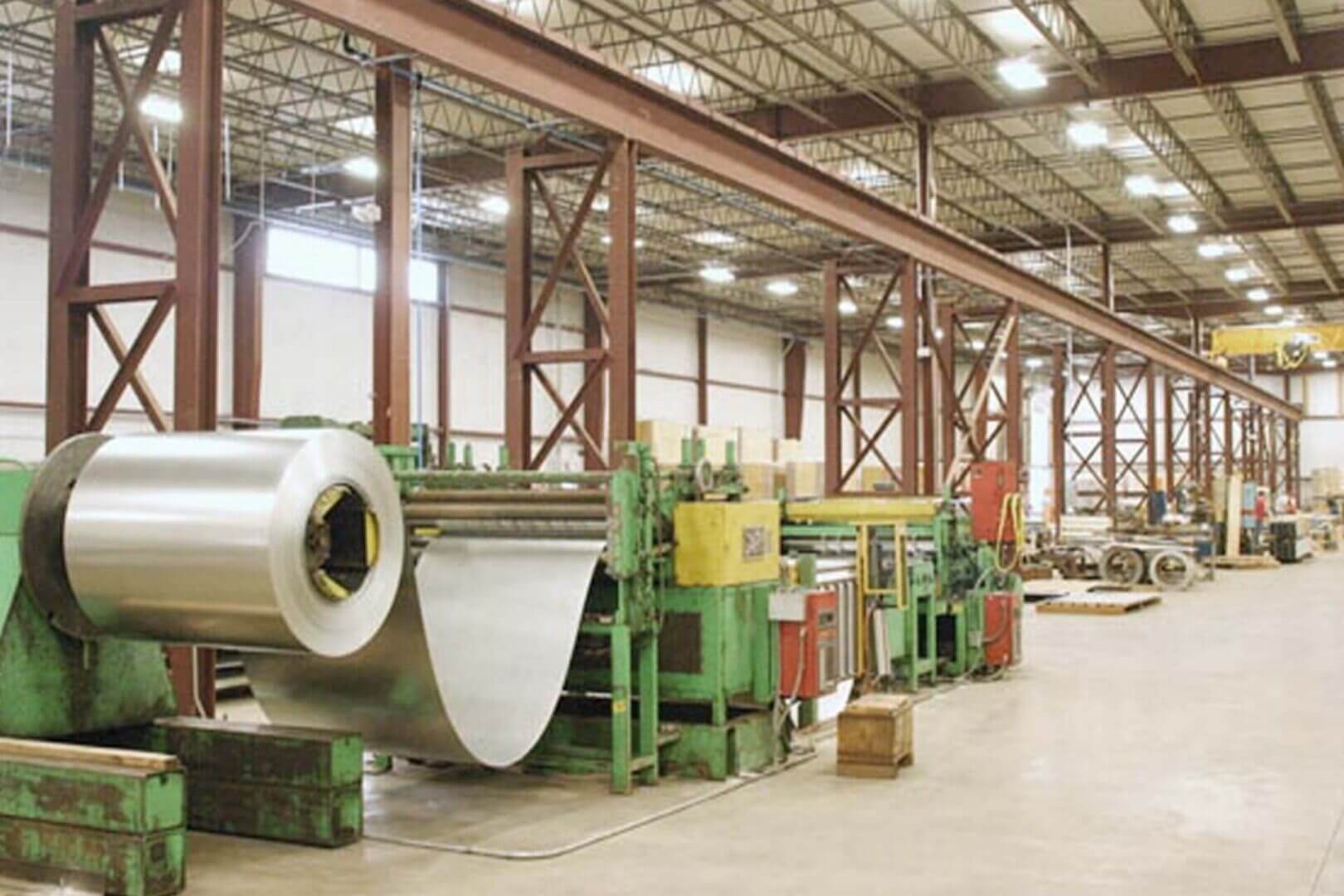 Large rolls of metal sheets in an industrial factory setting.