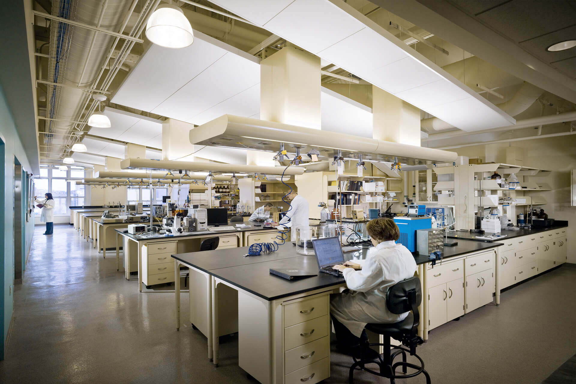 Scientist working alone in a spacious, modern laboratory filled with equipment.