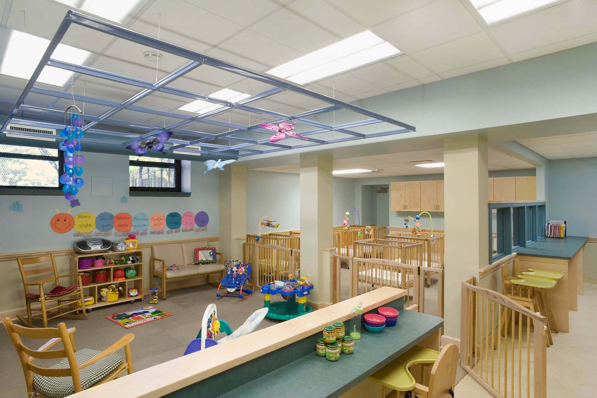 A spacious and colorful daycare room with toys and child-sized tables.