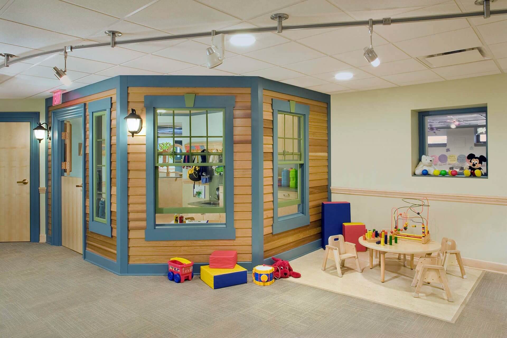 A colorful indoor playroom with toys and a playhouse.