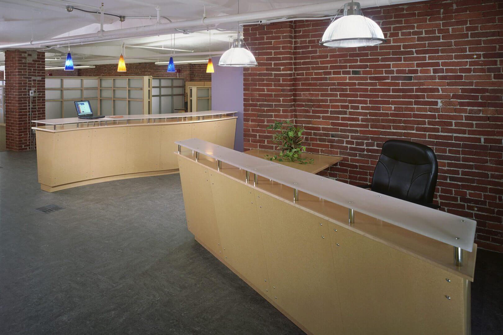 Reception desk area with brick wall and overhead lights.