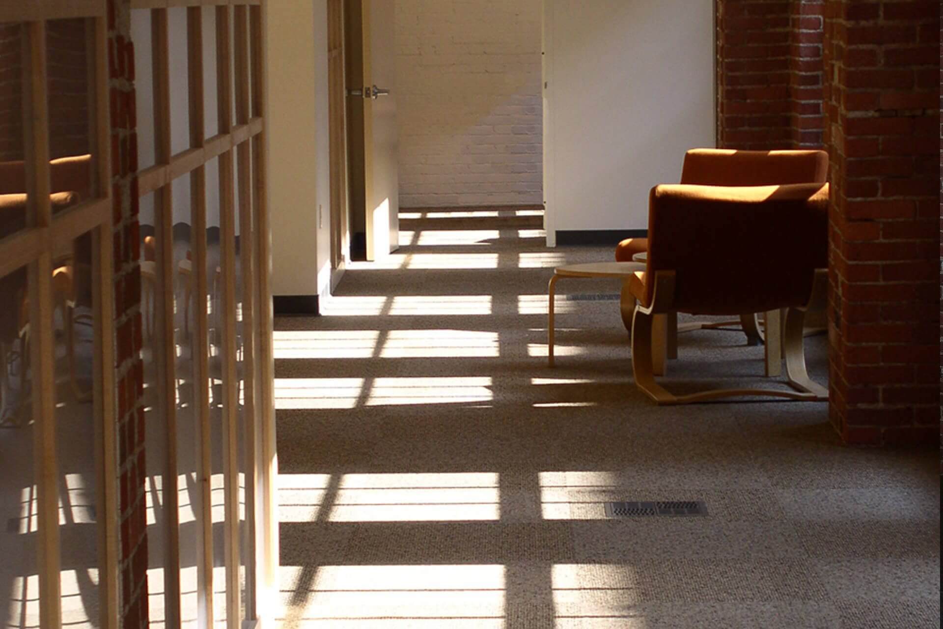 Sunlight casting shadows through windows onto a floor and chairs.