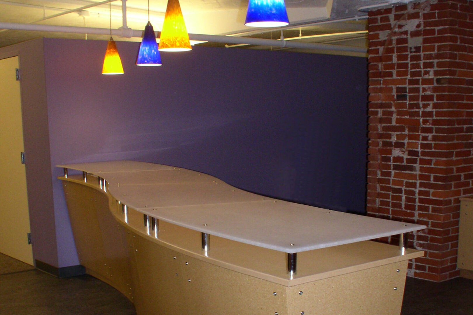 Modern bar counter with colorful pendant lights.