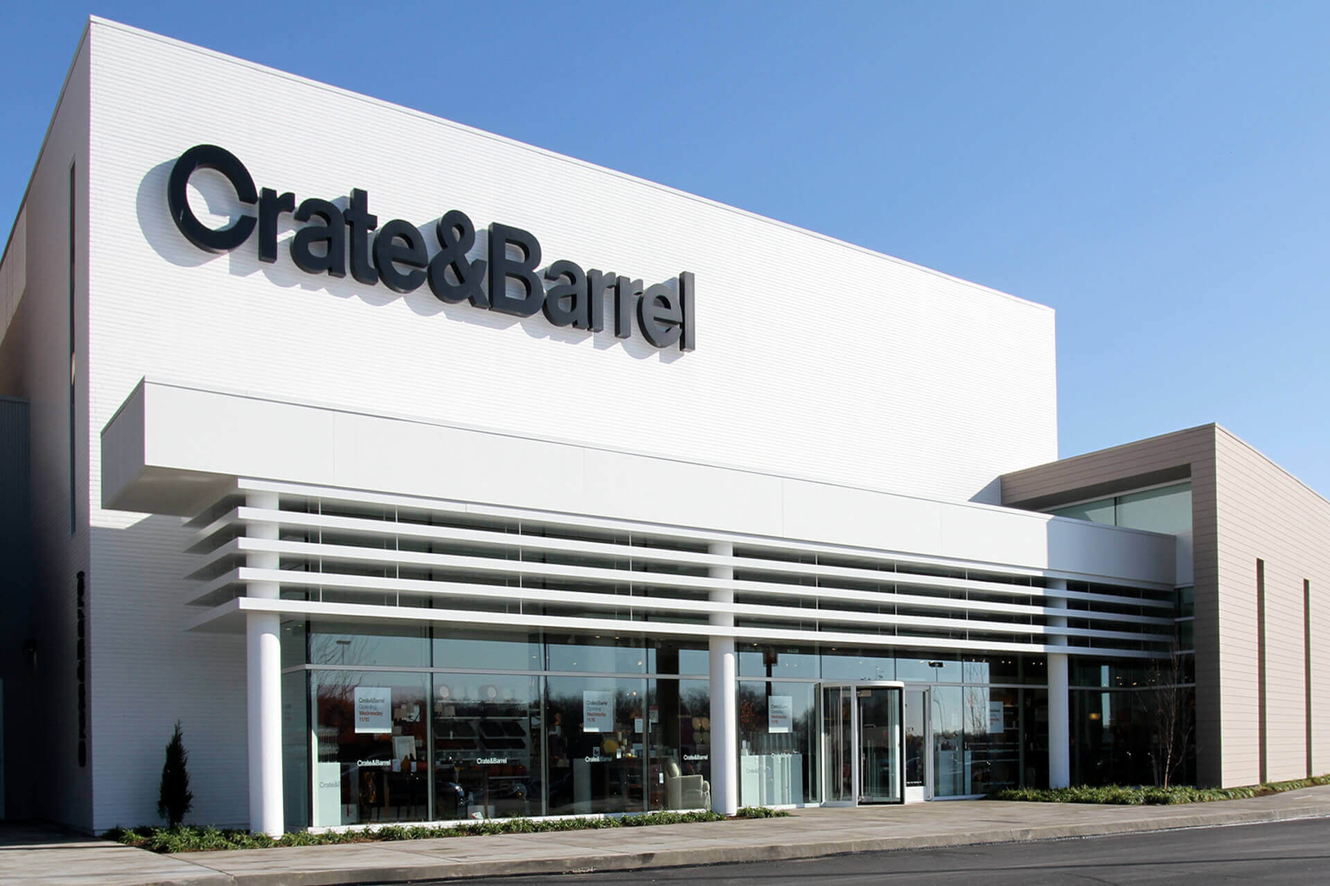 Exterior view of a Crate & Barrel store under a clear blue sky.