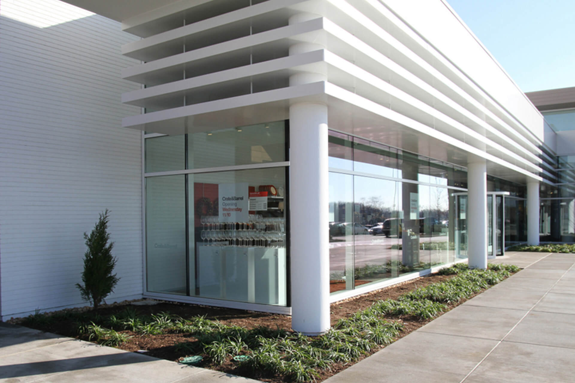 Modern building corner with large glass windows and horizontal white panels.