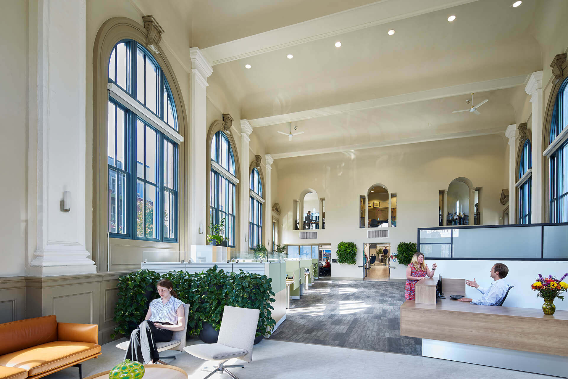 A bright, modern lounge with large arched windows and seating areas.
