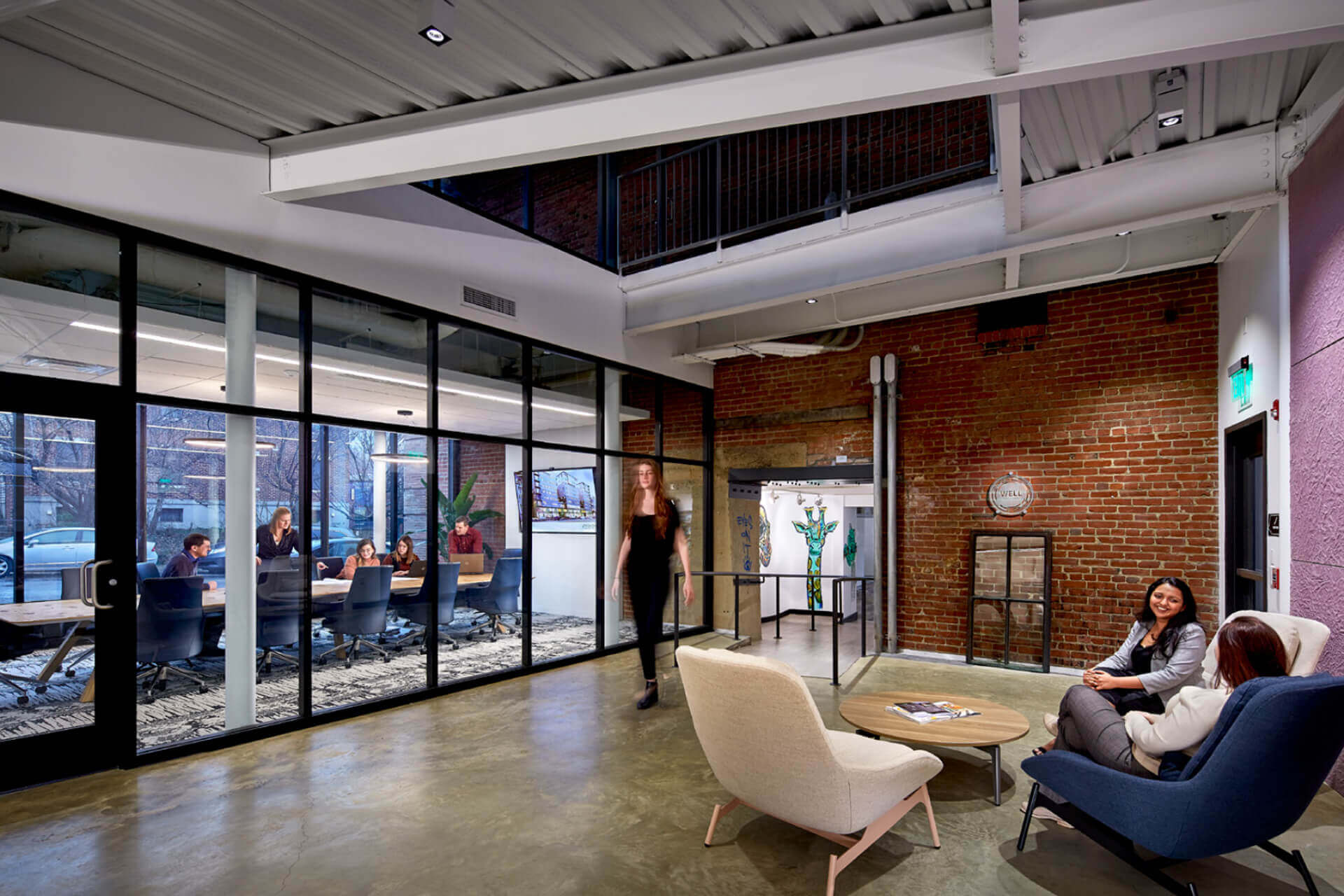 Modern office lounge with glass walls and comfortable seating.