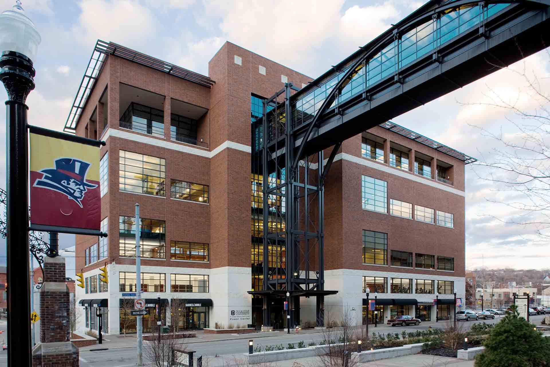 Modern brick building with a glass elevator and skybridge.