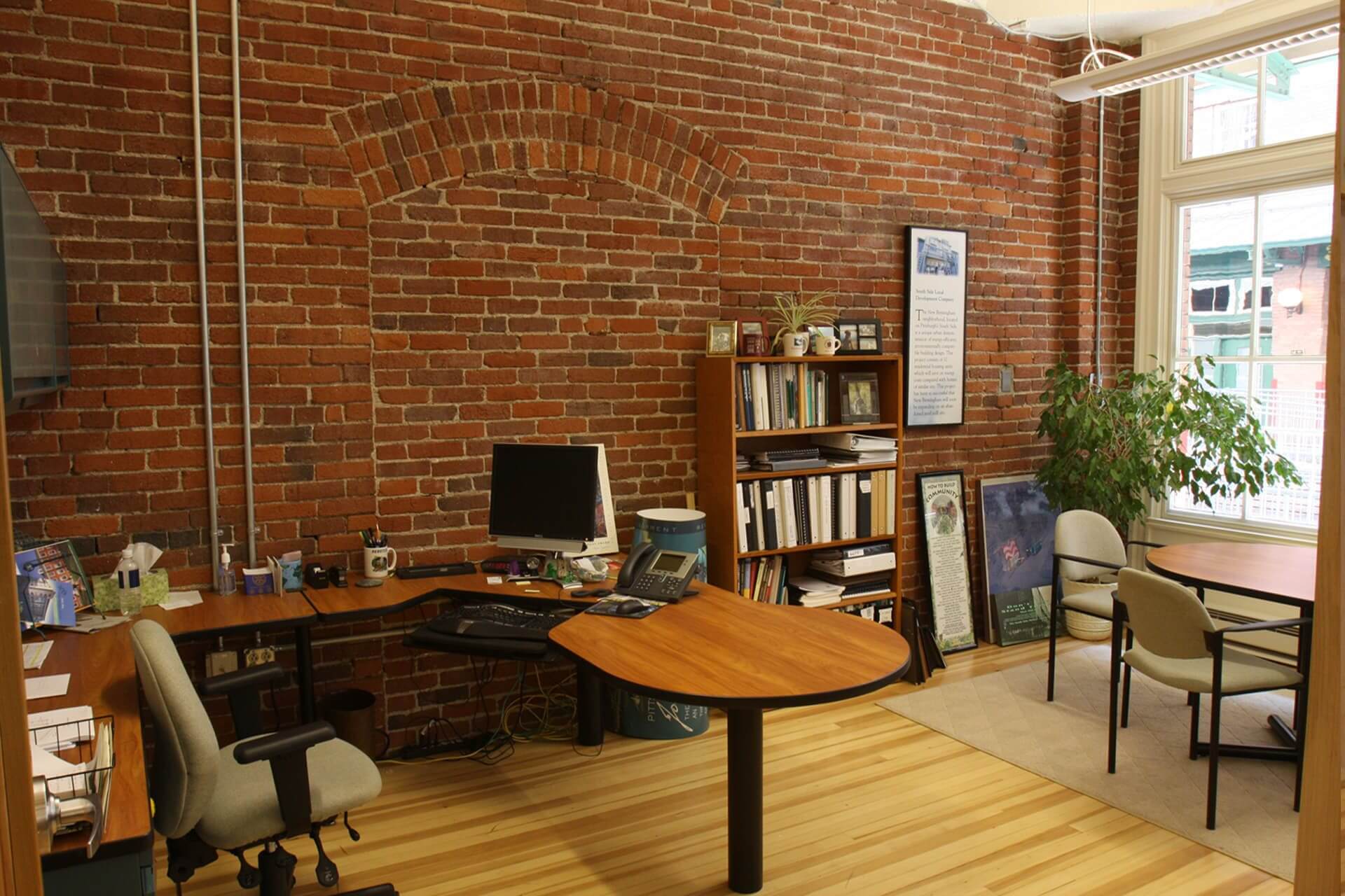 Cozy office with exposed brick walls and wooden furniture.