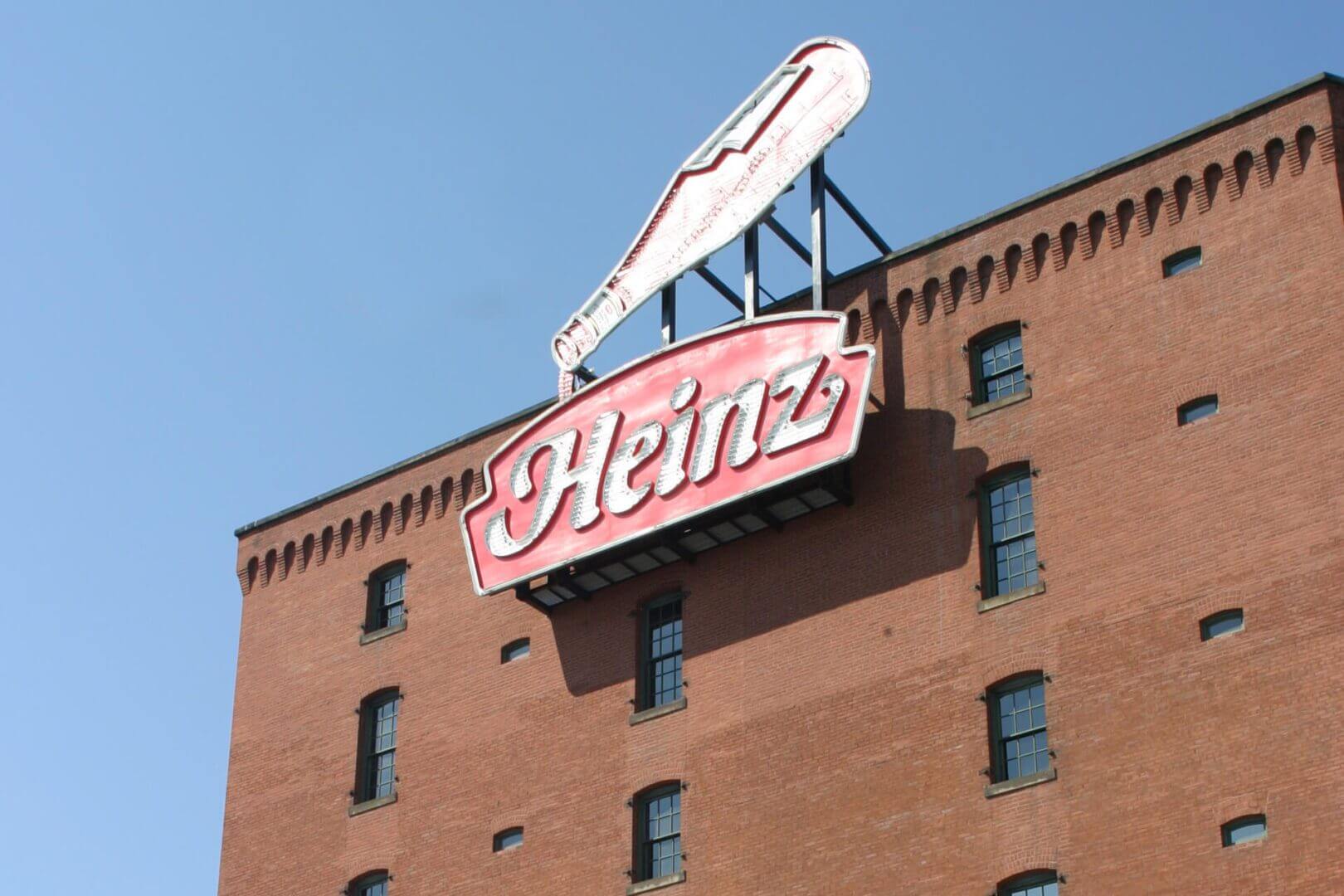 Heinz logo sign on a brick building under a clear blue sky.