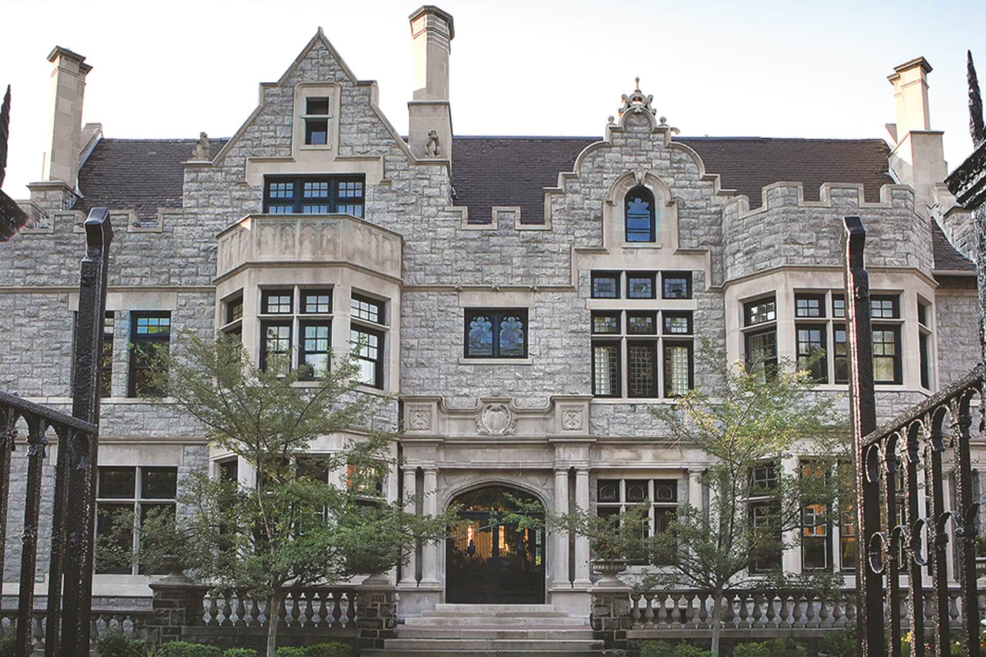A large historic stone mansion with ornate windows and a steep roof.