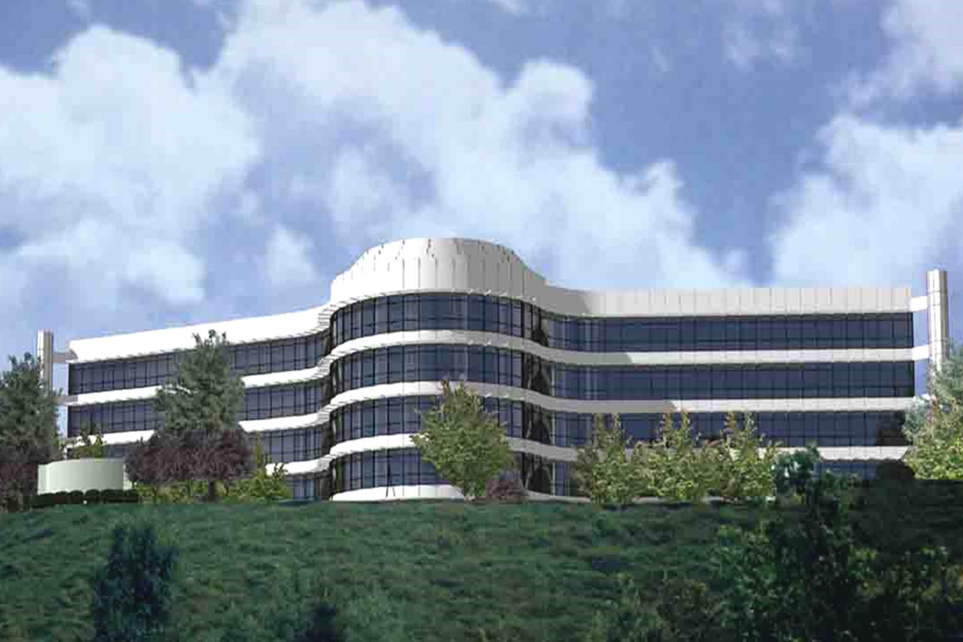 Modern curved glass office building with greenery in front under a partly cloudy sky.
