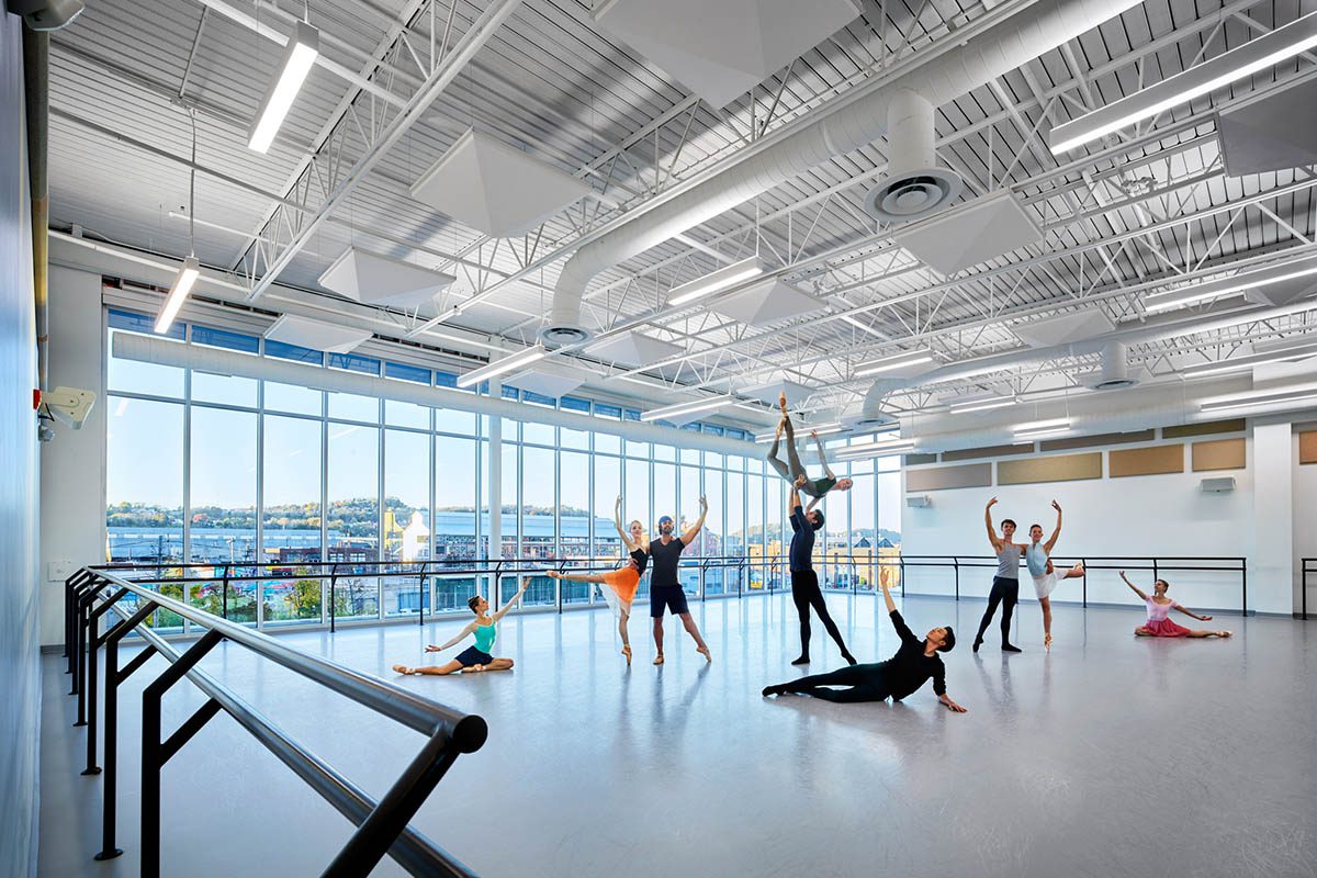 A group fitness class in a bright, spacious gym with large windows.