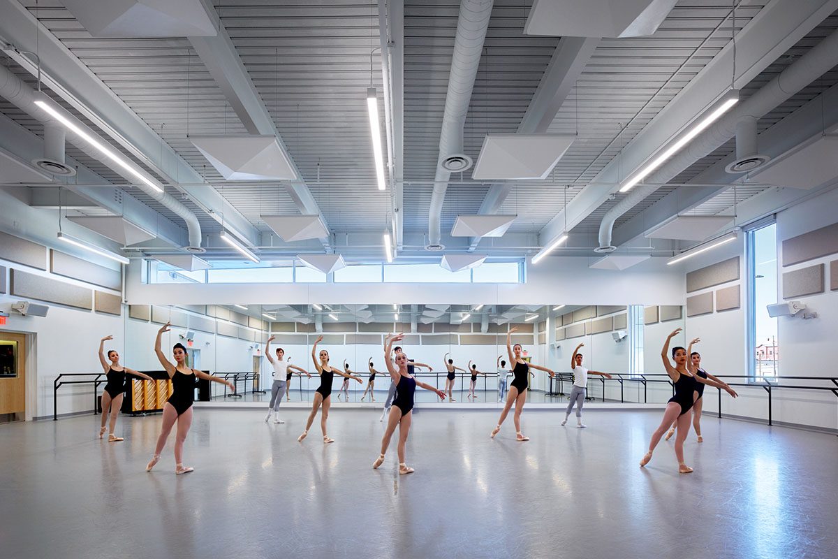 Ballet dancers practicing in a spacious, well-lit studio.