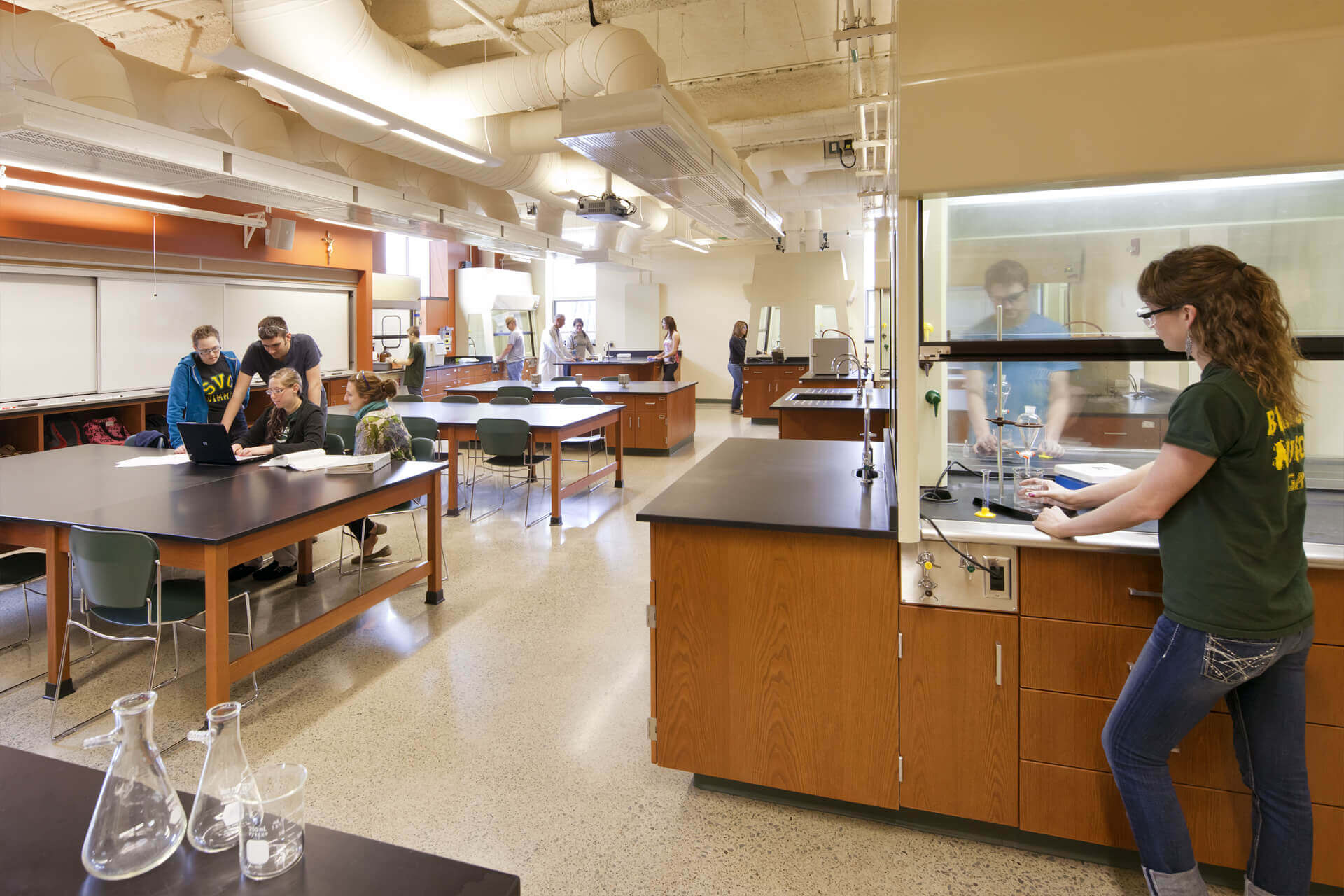 A spacious science classroom with wooden lab tables and students working.