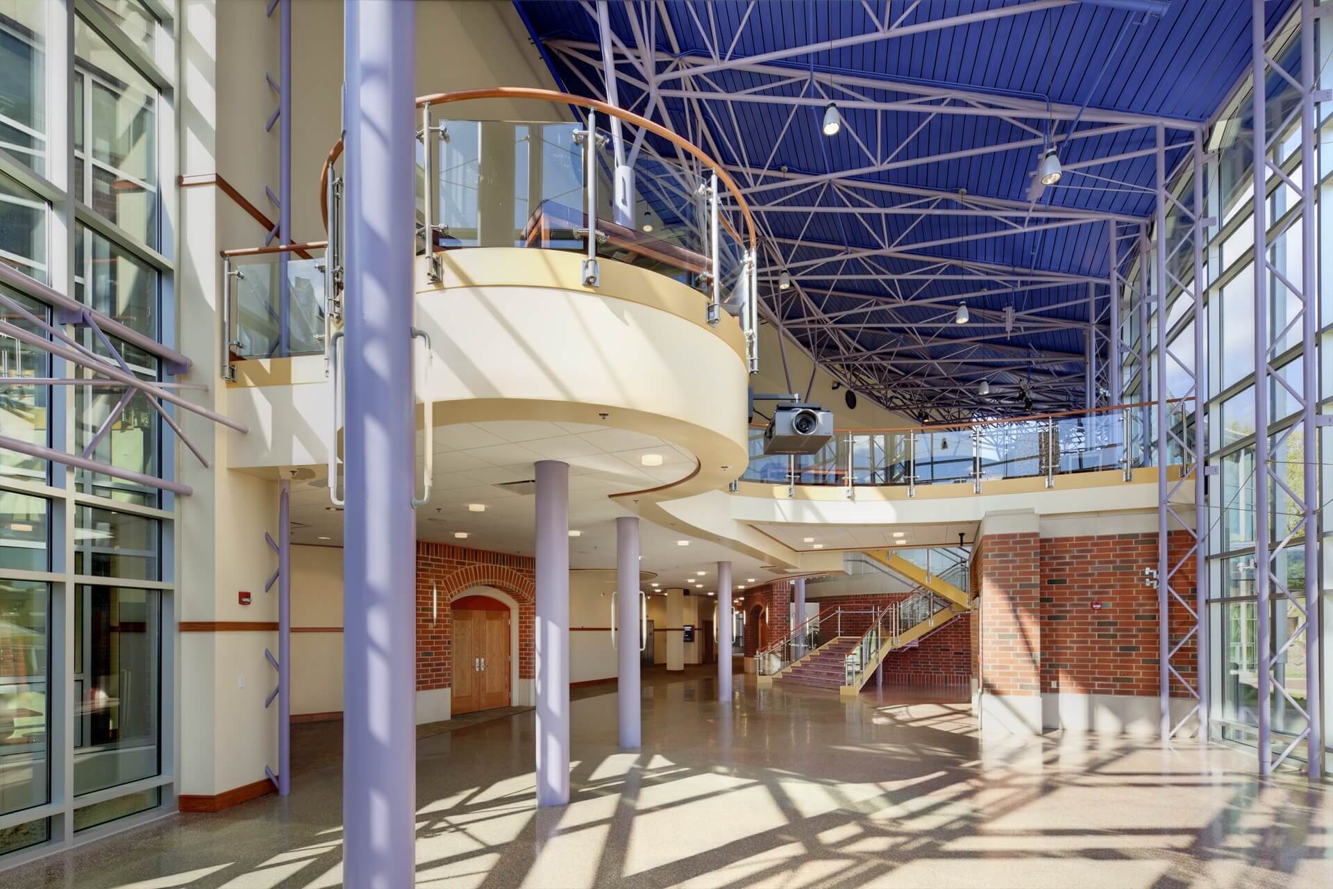 A spacious modern interior with curved balconies and blue ceiling.
