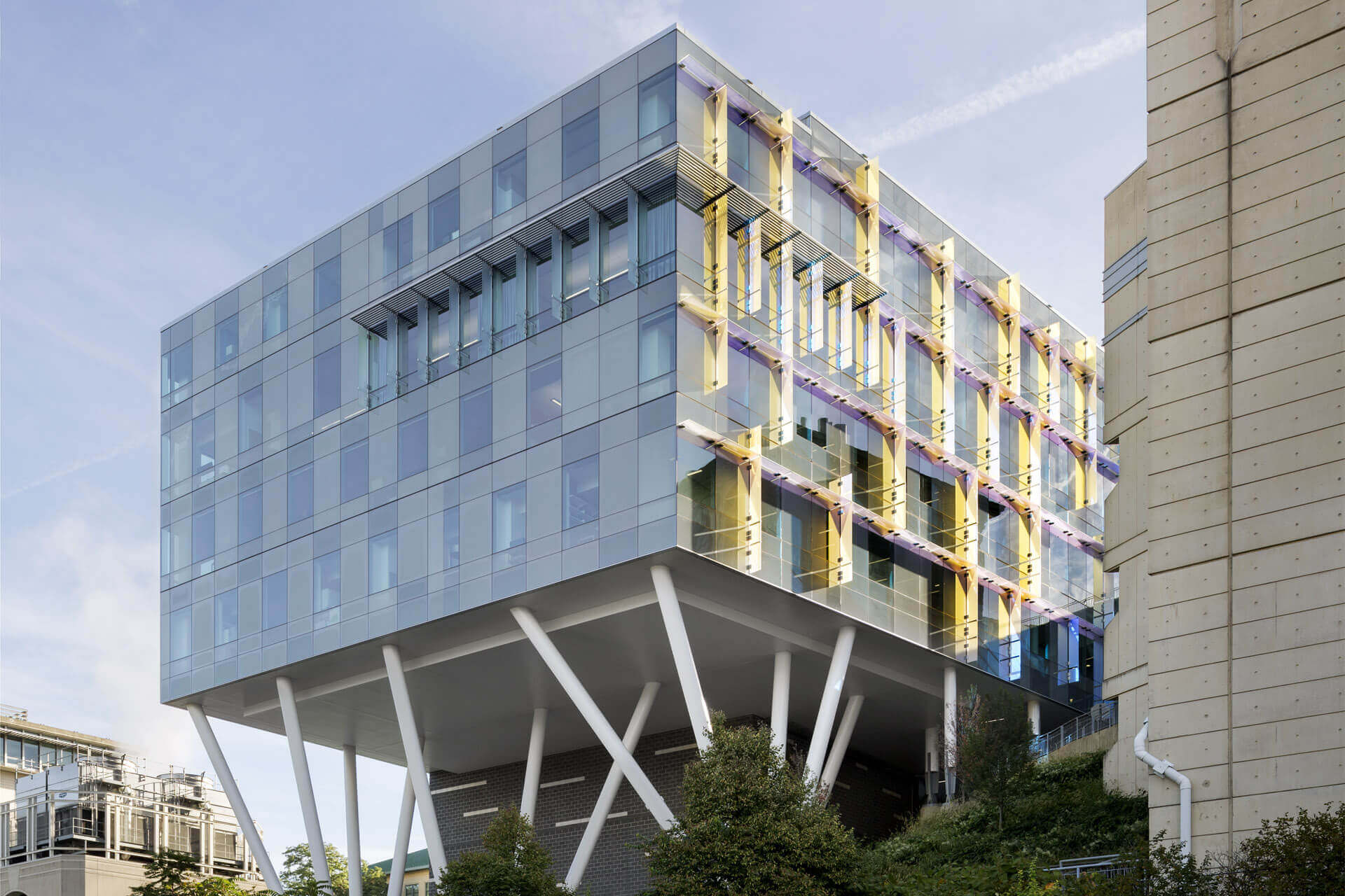 Modern glass office building with angled supports and yellow accents.