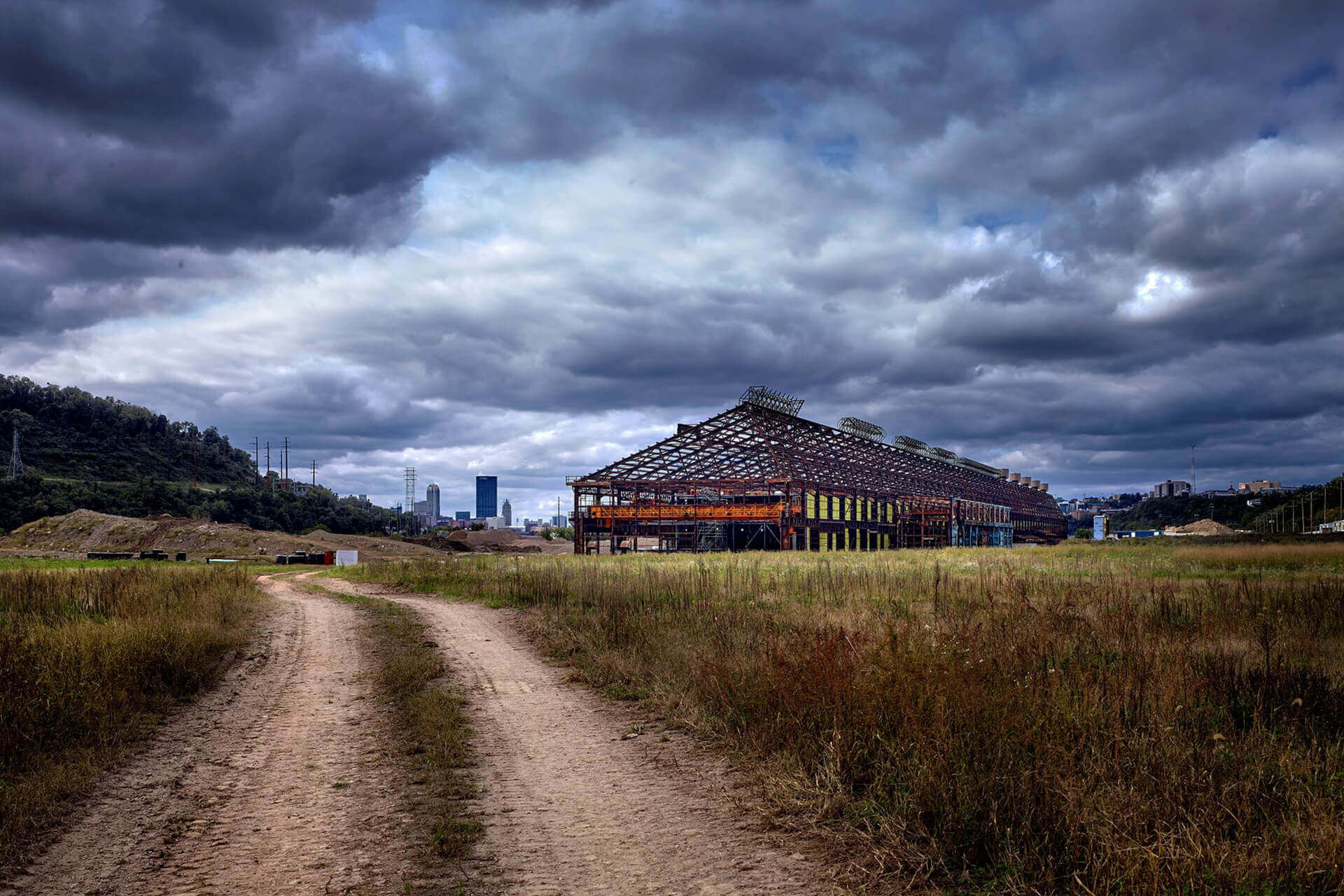 A path leads to an old wooden structure under a cloudy sky.