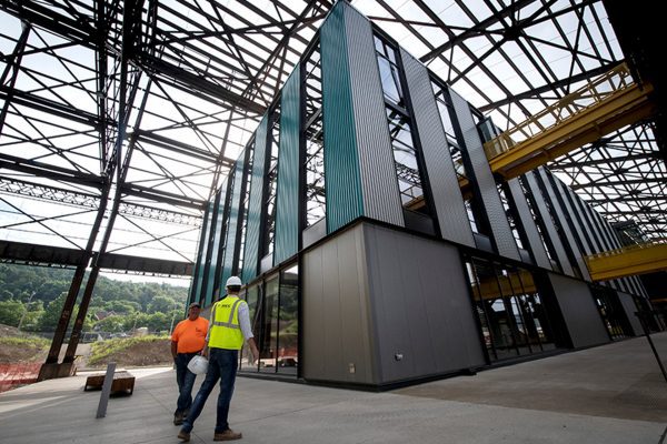 Two construction workers walk near a modern building under construction.