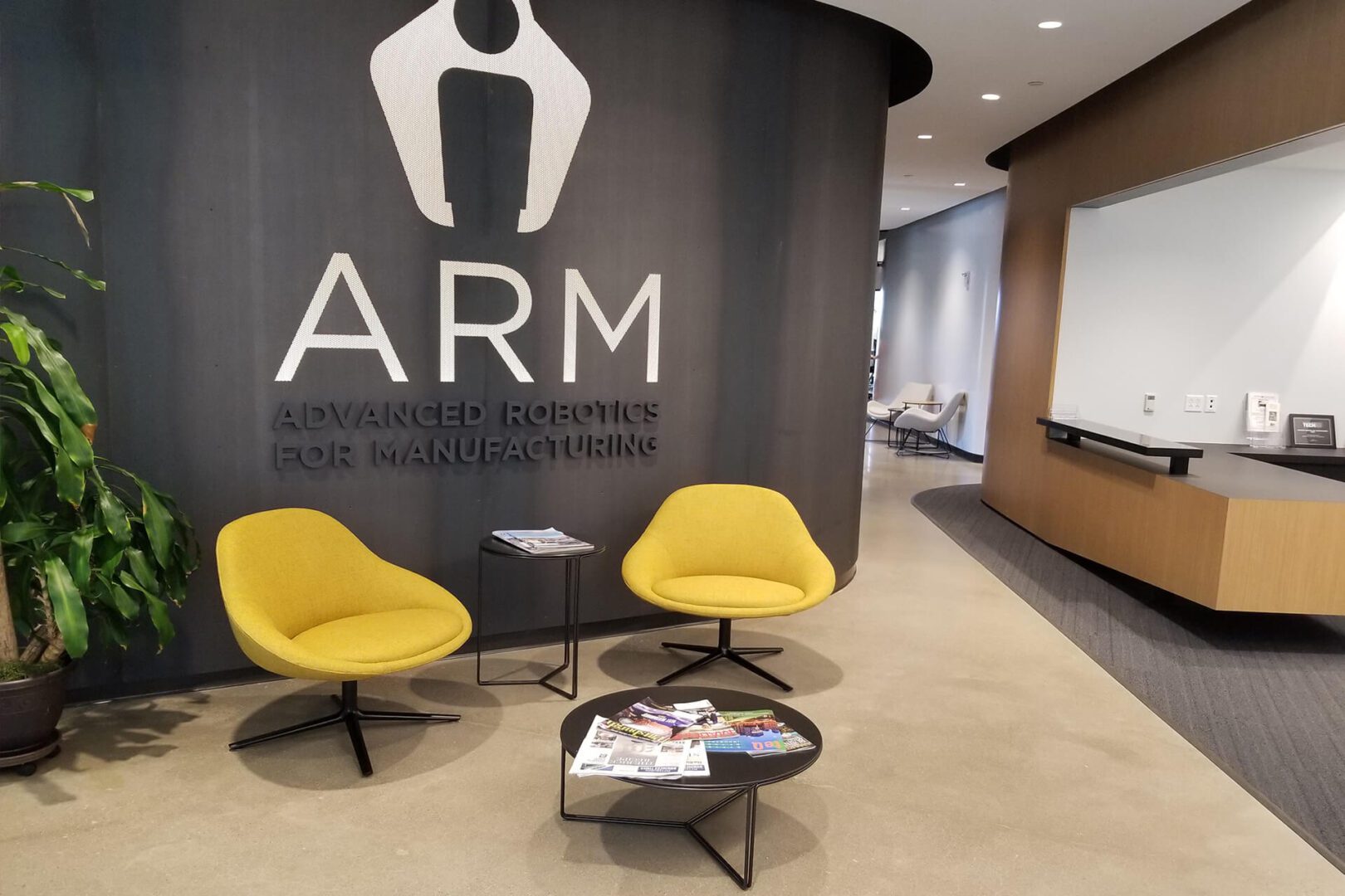 Modern office lounge with yellow chairs and ARM logo on wall.