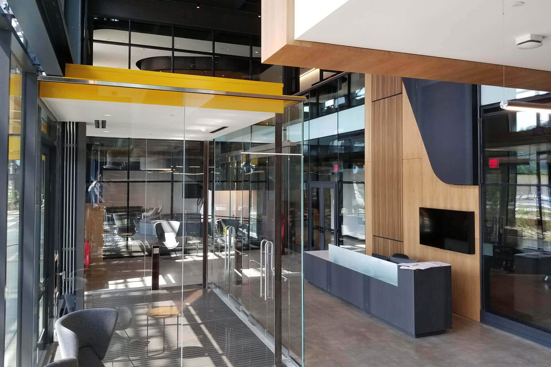 Modern office lobby with glass walls and wooden accents.