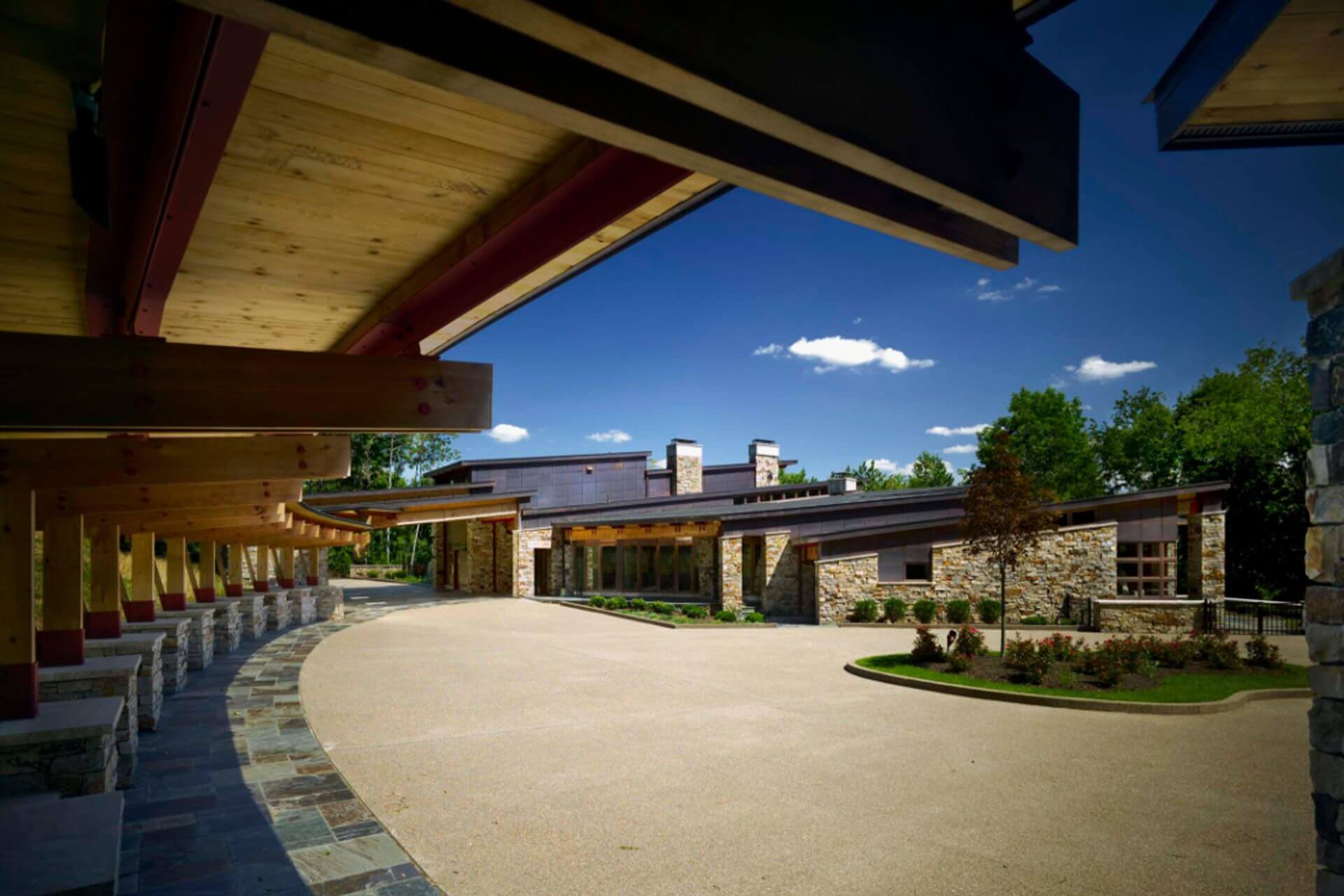 A modern outdoor patio with wooden ceiling and curved stone seating area.