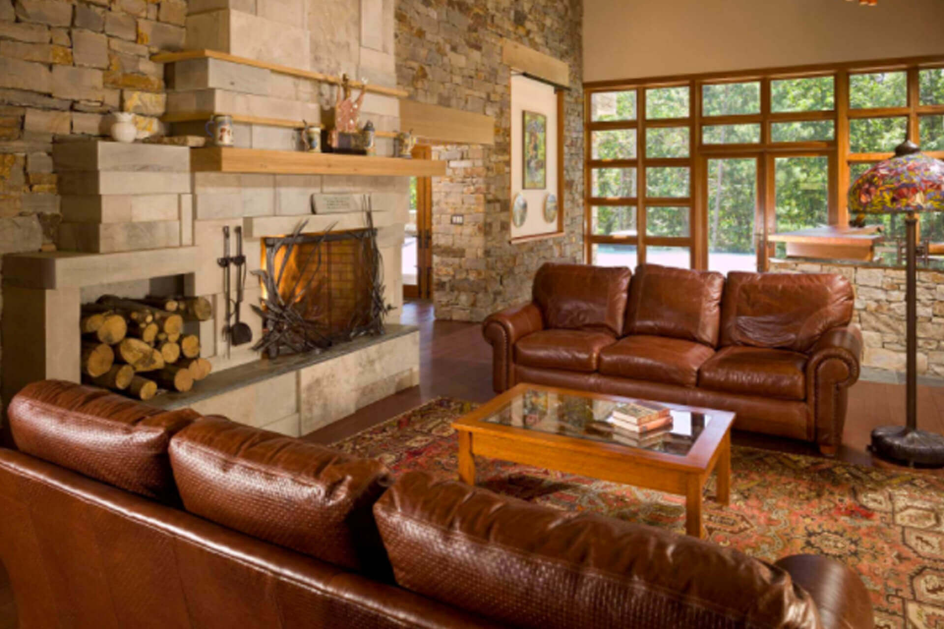 Cozy living room with leather sofas and a stone fireplace.