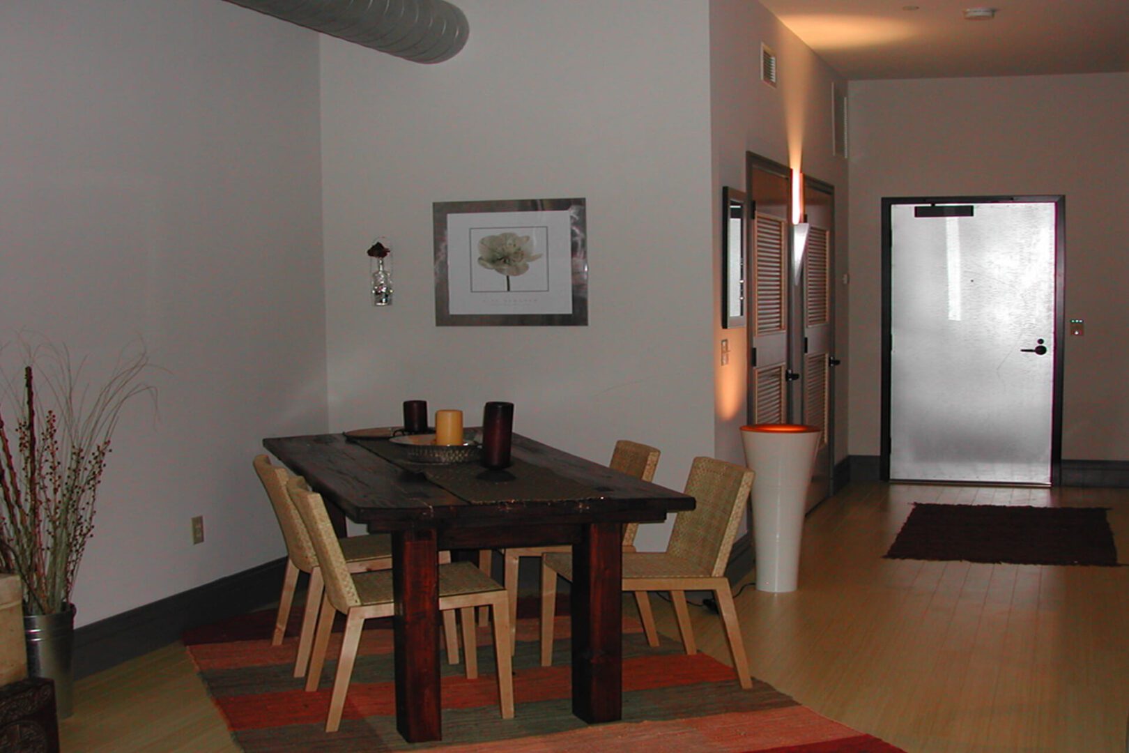 A dining table with chairs in a modern room with a painting and lamp.