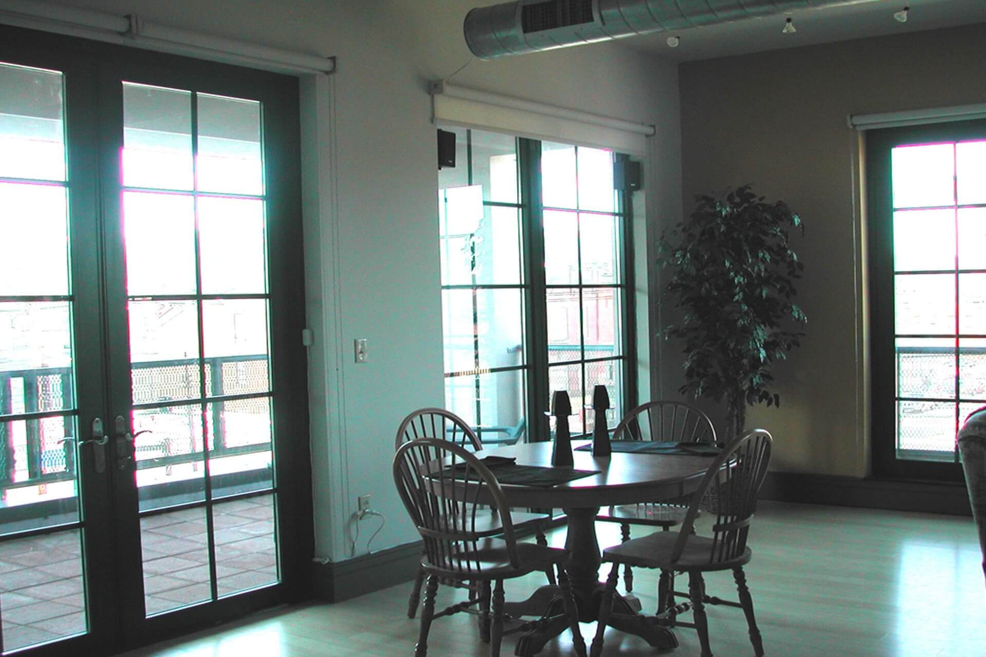 A dining table with four chairs near large glass doors.