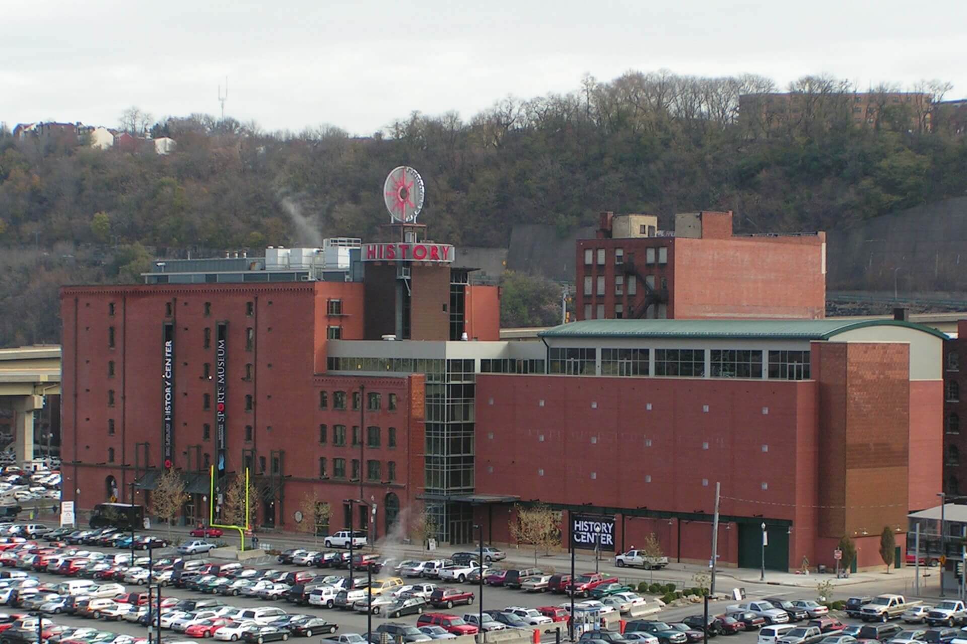 A large brick hospital building with a parking lot in front.