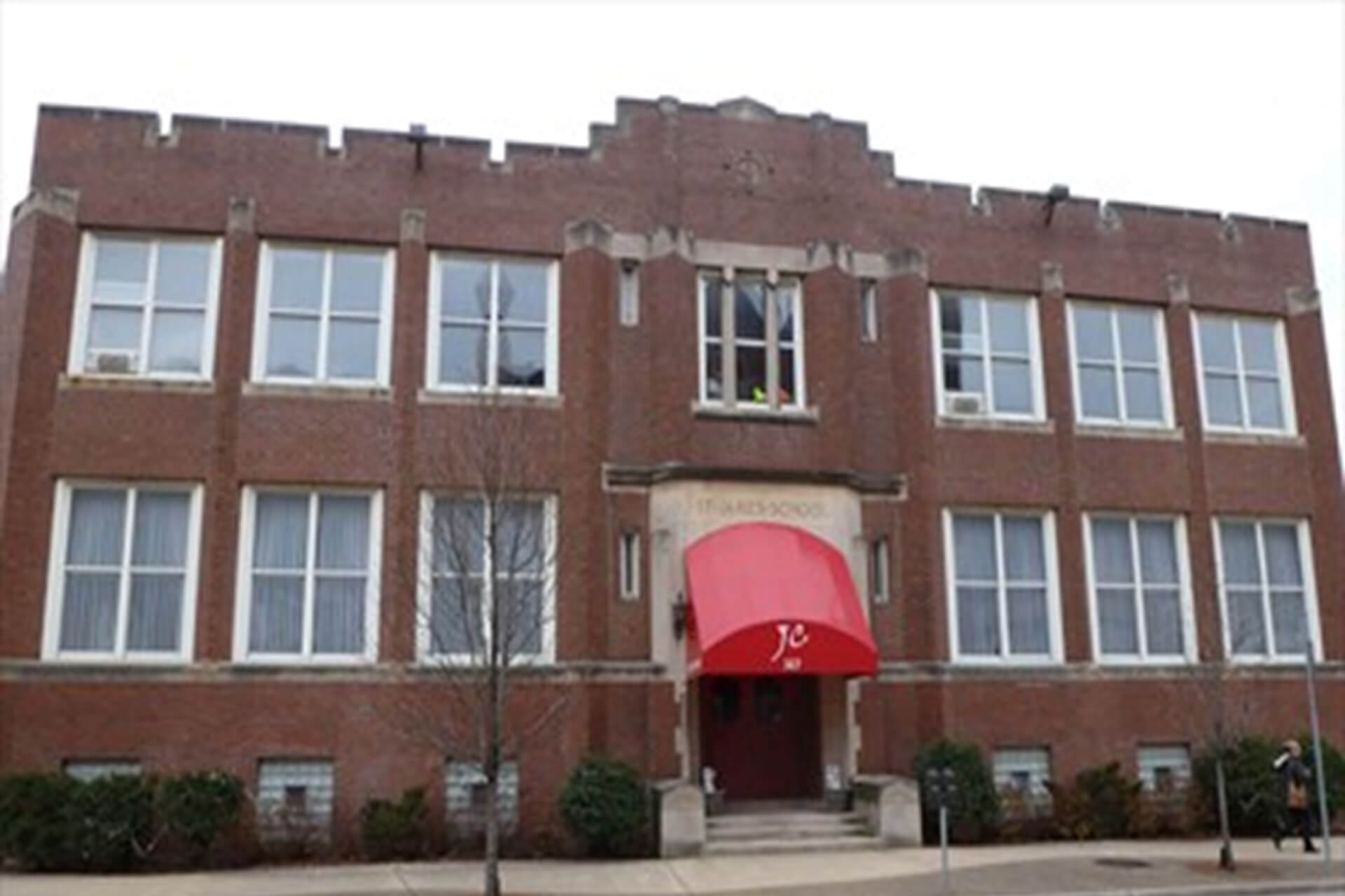 Entrance of a brick building with a red awning.