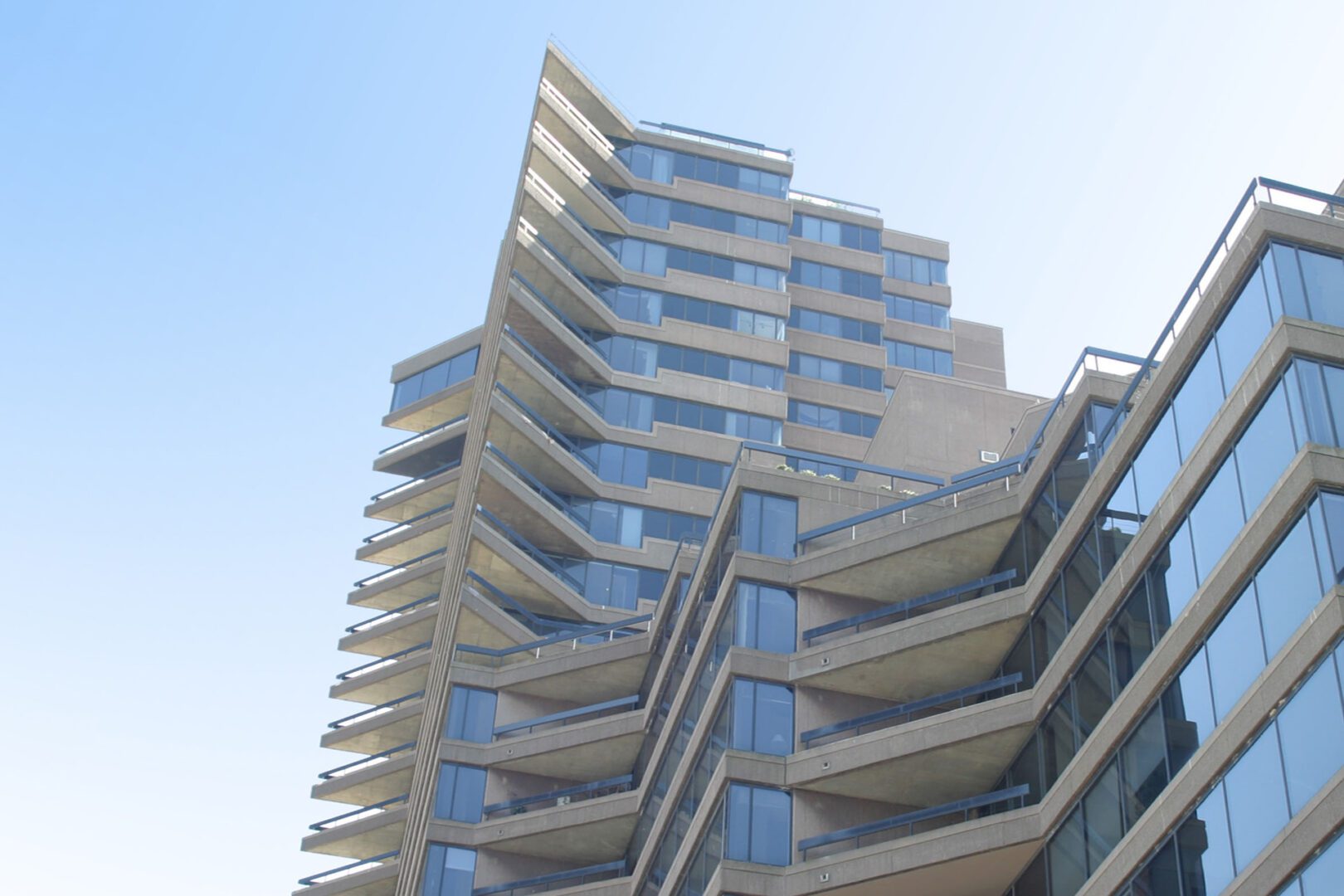 Modern high-rise building with unique angular balconies under a clear sky.