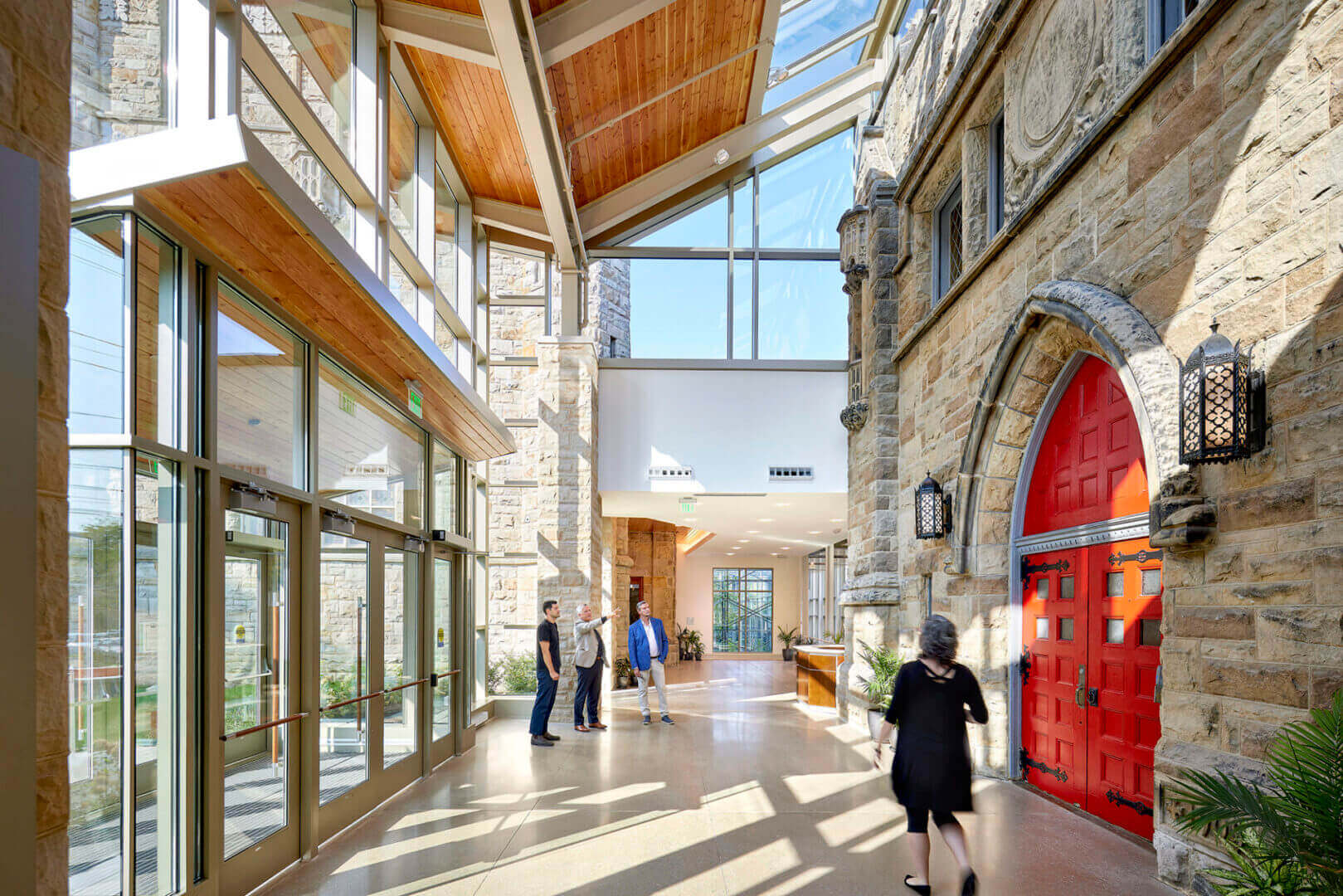 Modern atrium with people and red door.