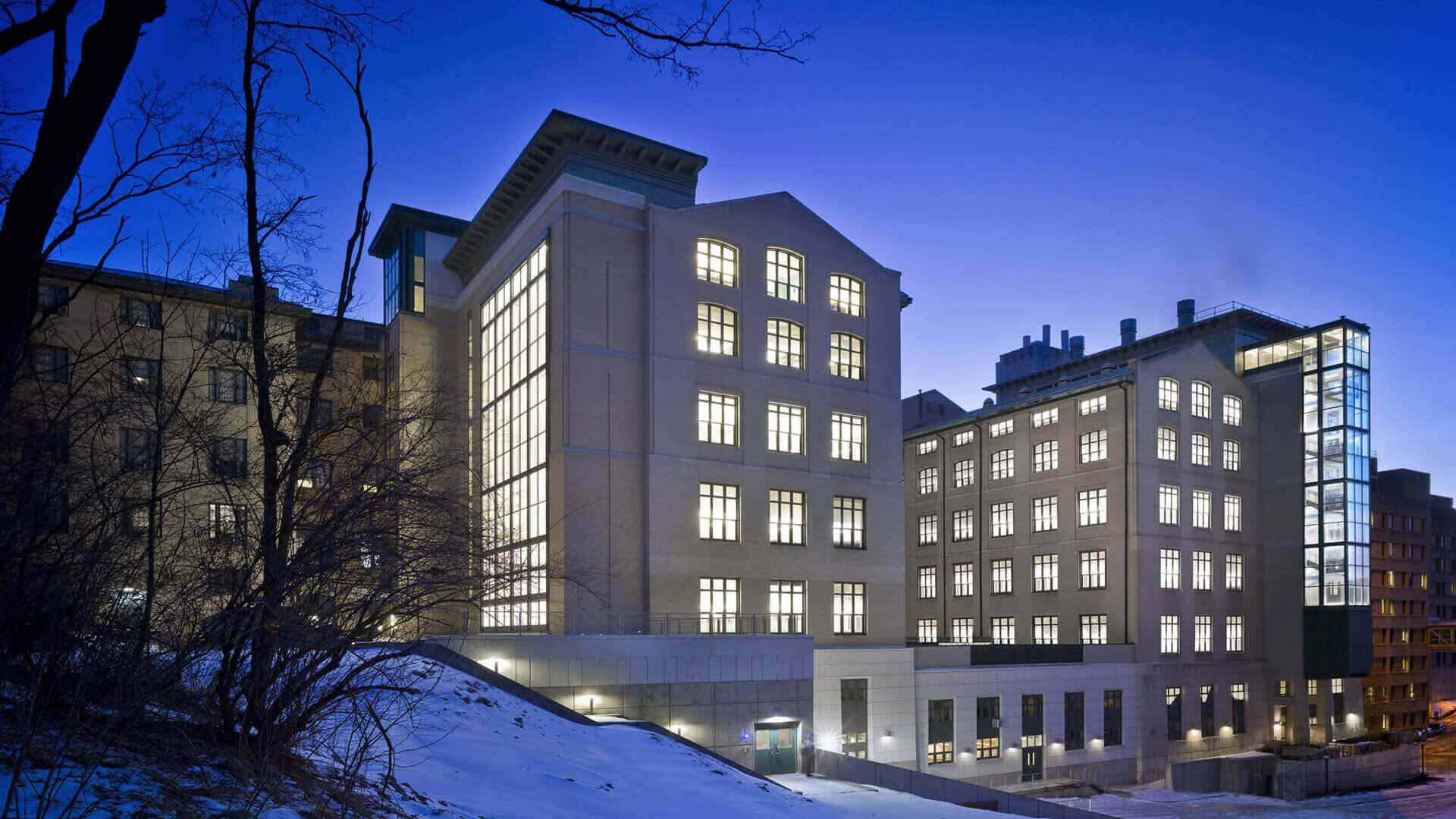 Snow-covered modern university building illuminated at dusk