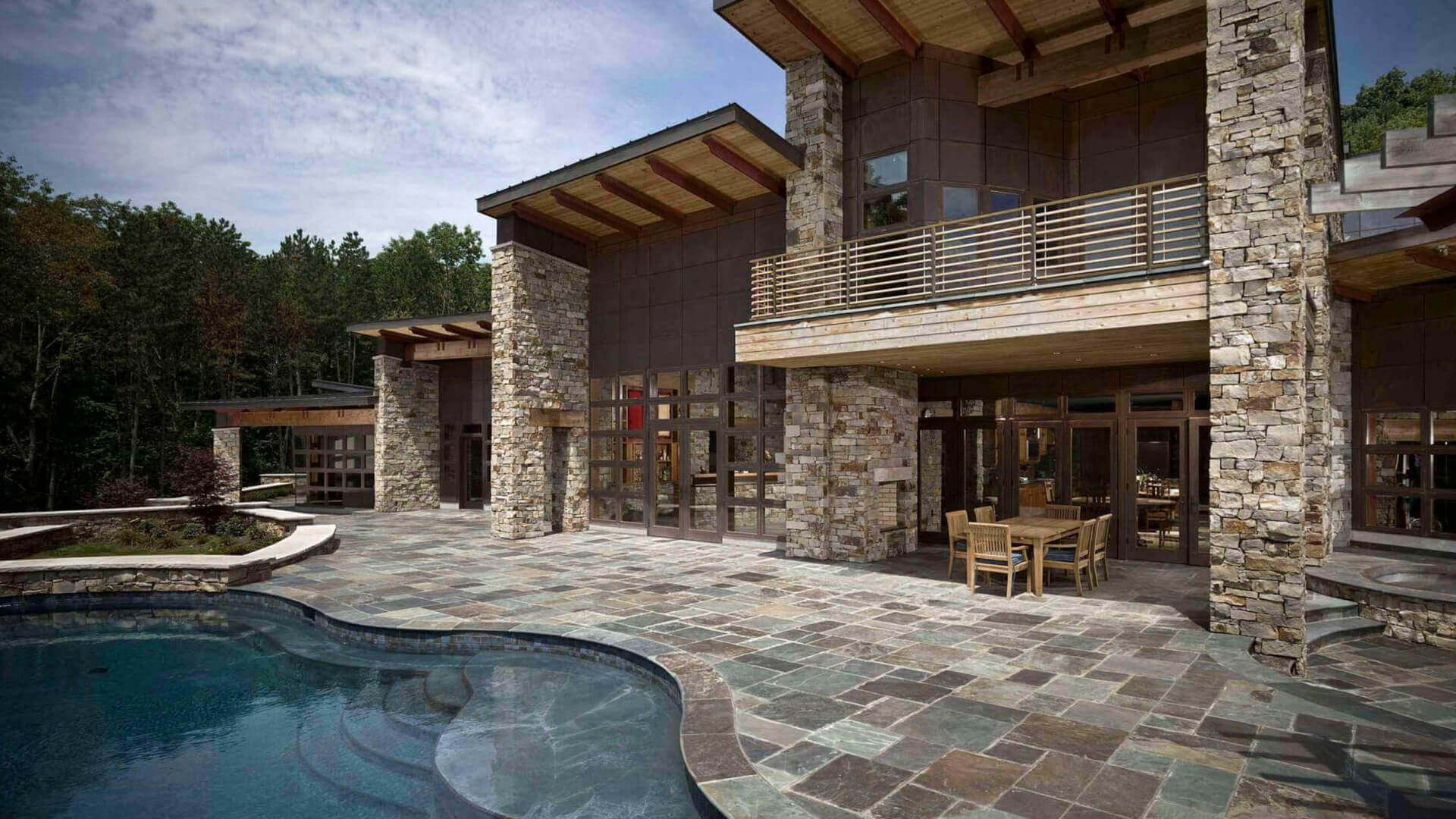 Contemporary stone house patio with curved pool